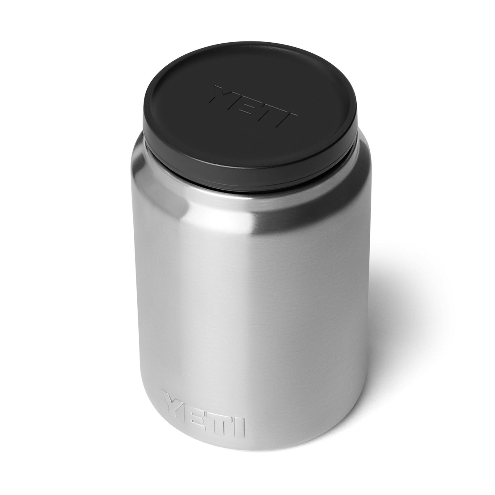 Der YETI® Isolierter Essensbehälter Rambler 24 oz aus Edelstahl mit schwarzem Deckel und geprägt mit dem YETI Logo hat eine doppelwandige Vakuumisolierung, gezeigt vor weißem Hintergrund.