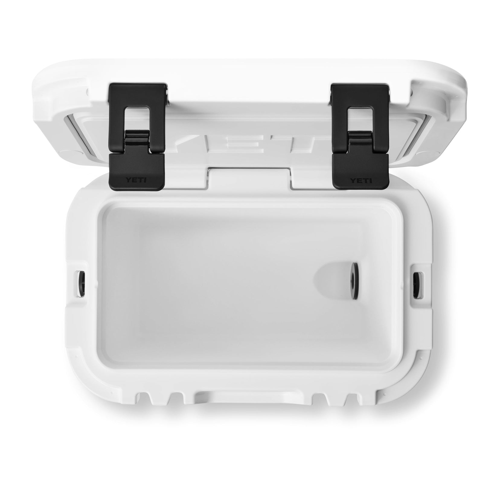 Draufsicht auf eine geöffnete YETI® Kühlbox Roadie 15 - Weiß mit schwarzen Verschlüssen und leerem Innenraum. Der Deckel ist an der Rückseite aufklappbar und der Ablassstopfen befindet sich an der rechten Seite dieser kompakten, tragbaren Kühlbox von YETI.
