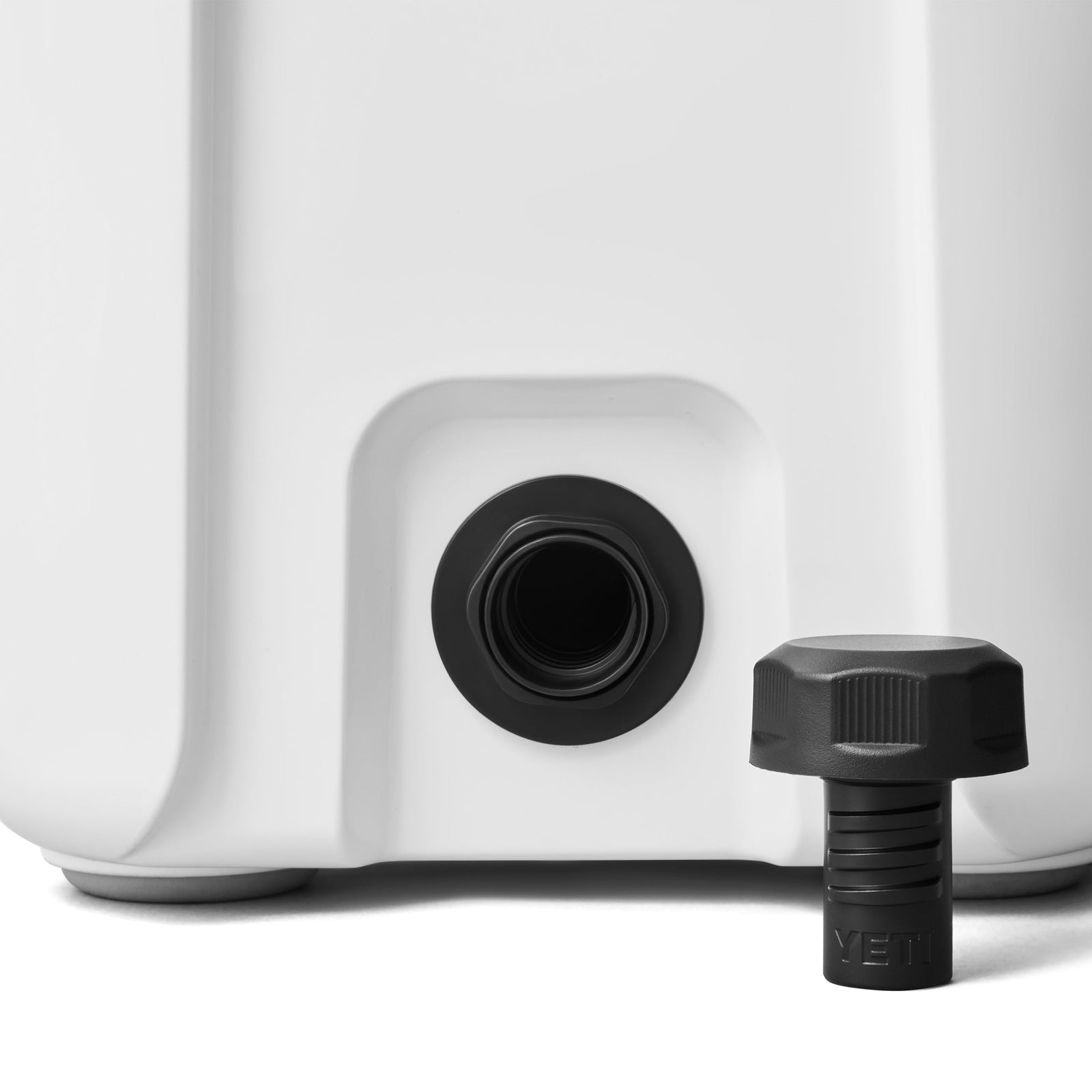 Nahaufnahme der YETI® Kühlbox Roadie 15 - White mit abgenommenem schwarzen Schraubdeckel, der die Gewindeöffnung zeigt. Der Deckel steht aufrecht auf der rechten Seite und ist somit ideal für Ihr nächstes mobiles Abenteuer mit YETI.