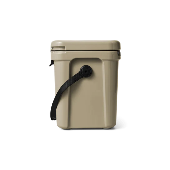 Die YETI® Kühlbox Roadie 24 in Tan, eine rechteckige Kühlbox mit schwarzem Trageriemen an der Seite, wird vor einem schlichten weißen Hintergrund präsentiert.