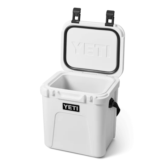 Weiße YETI® Kühlbox Roadie 24 mit offenem Deckel zeigt den leeren Innenraum. Mit schwarzen Verschlüssen, seitlichem Griff und geprägtem YETI-Logo; PermaFrost™-Isolierung hält den Inhalt länger kalt. Marke: YETI.