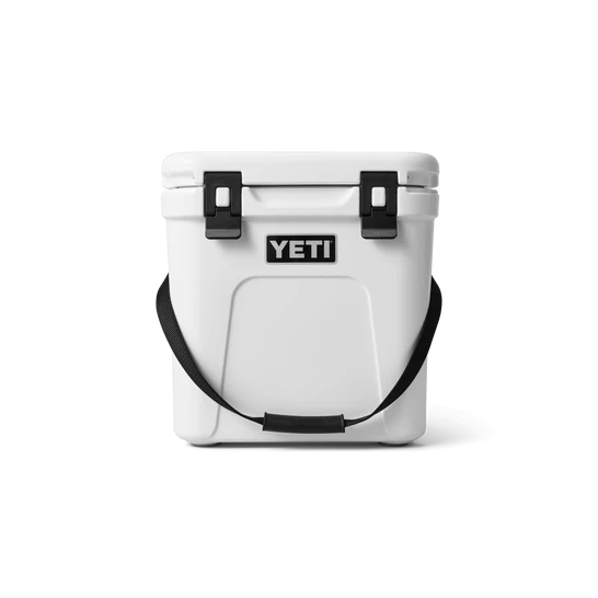 Die YETI® Kühlbox Roadie 24 in Weiß von YETI verfügt über PermaFrost-Isolierung, einen schwarzen Schultergurt und zwei schwarze Verschlüsse am Deckel - präsentiert vor weißem Hintergrund.