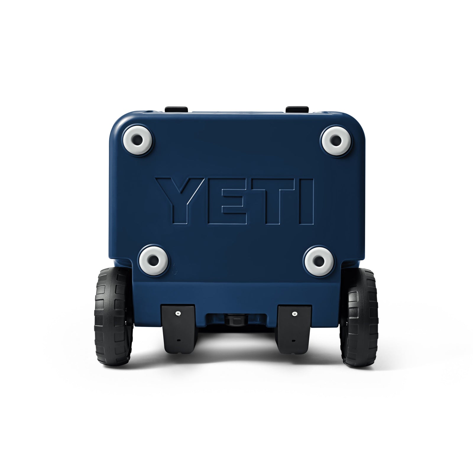 Die YETI® Kühlbox Roadie 48 - Navy steht aufrecht auf zwei großen schwarzen Rädern. Auf der Rückseite ist das YETI-Logo eingeprägt und an jeder Ecke befinden sich vier runde silberne Akzente.