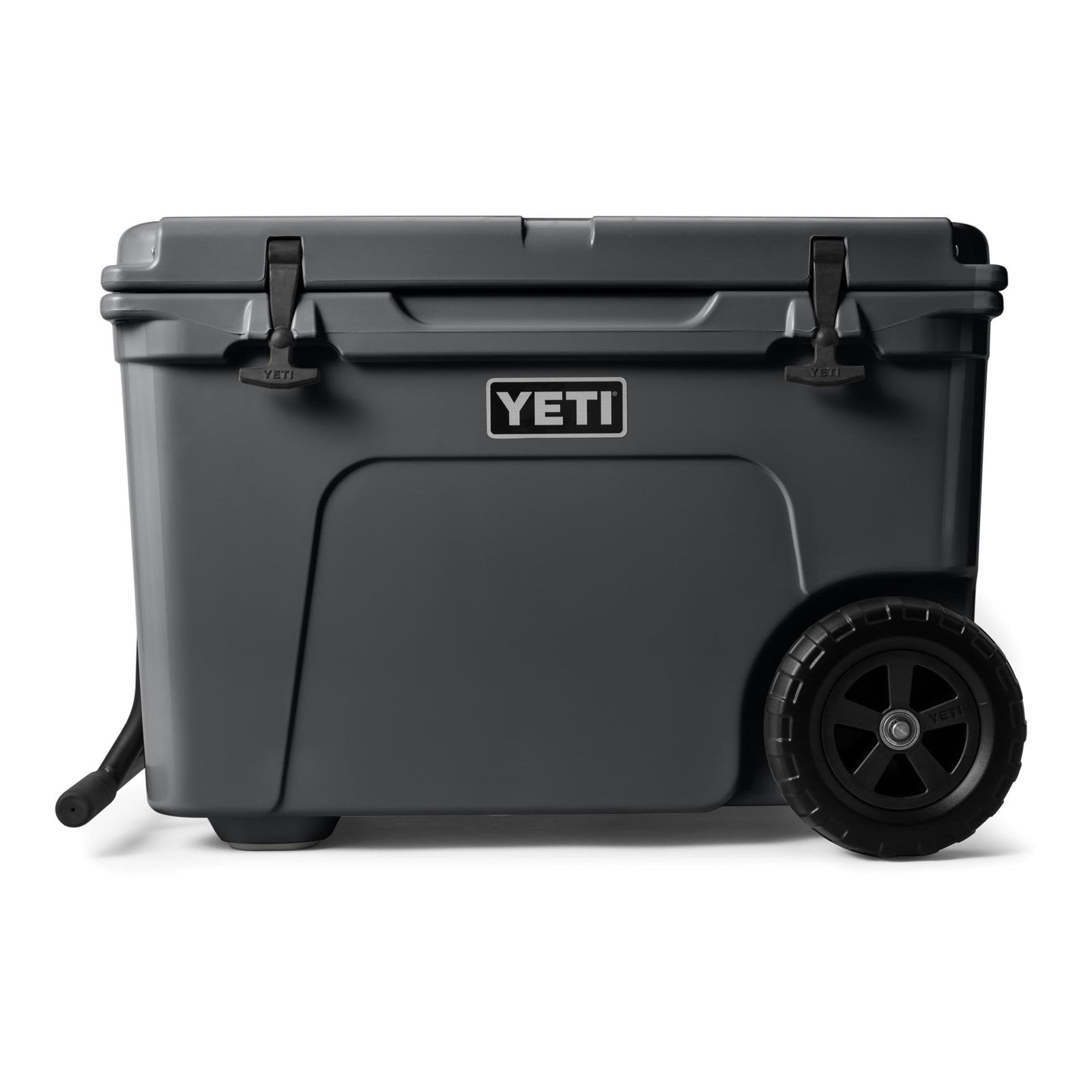 Die YETI® Kühlbox Tundra Haul - Charcoal ist eine große, dunkelgraue Kühlbox mit aufklappbarem Deckel, schwarzen Verschlüssen und stabilen Rädern an einer Seite, was sie zur idealen rollbaren Outdoor-Kühlbox für den einfachen Transport macht.