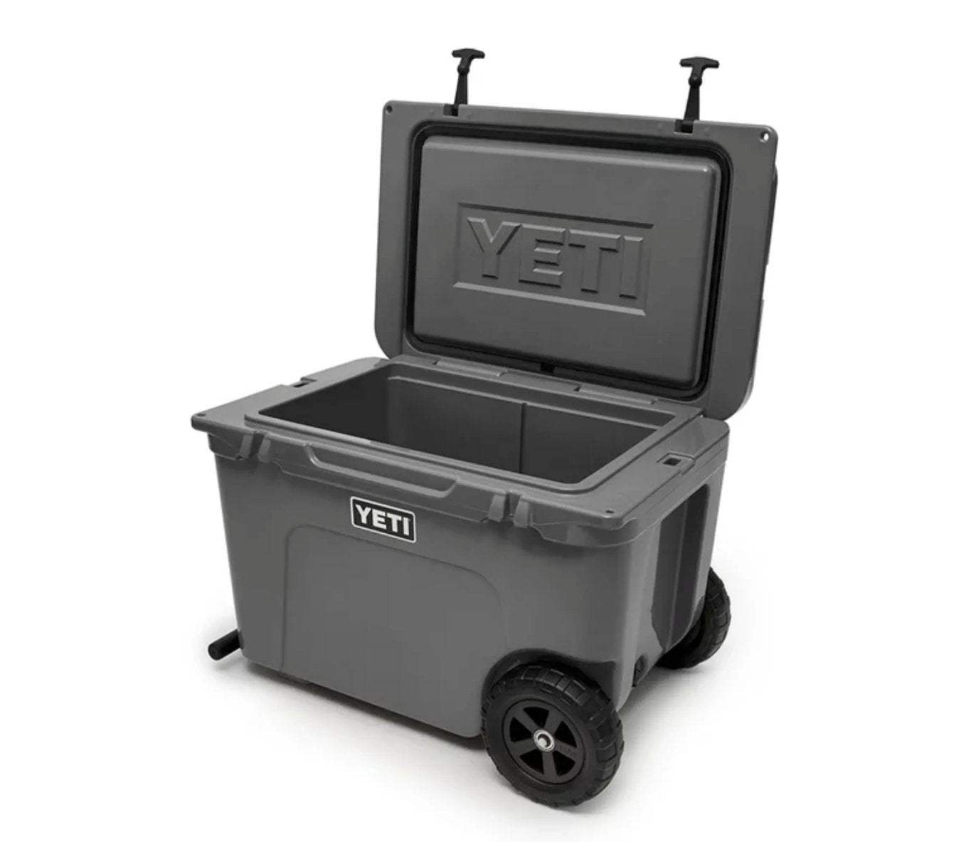 Die YETI® Kühlbox Tundra Haul - Charcoal ist eine große, rollbare Kühlbox mit stabilen Rädern, einem Griff für den einfachen Transport und einem Klappdeckel, der sich öffnen lässt und einen leeren Innenraum freigibt; das YETI-Logo befindet sich auf der Vorderseite und der Innenseite des Deckels.