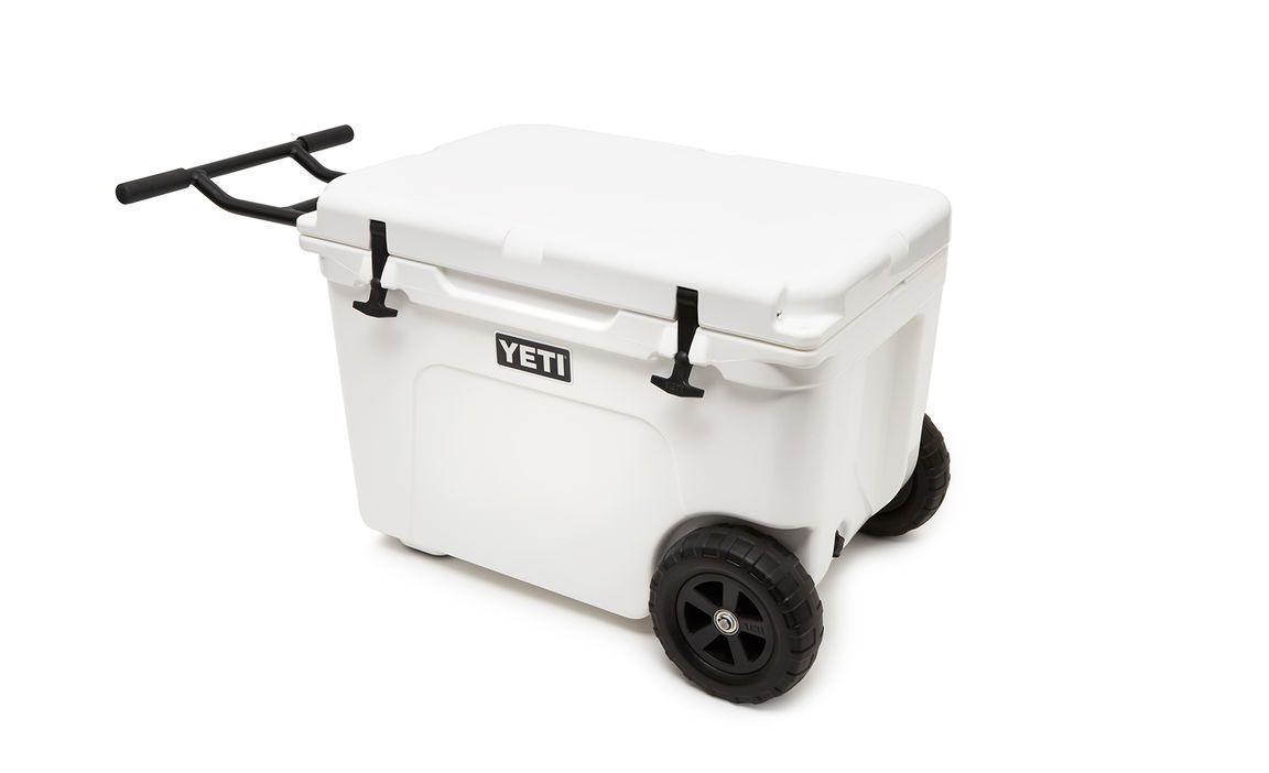 Die YETI® Kühlbox Tundra Haul - White ist eine robuste Kühlbox mit Rädern, schwarzen Griffen, einem geschlossenen Deckel und zwei stabilen schwarzen Rädern für den einfachen Transport.