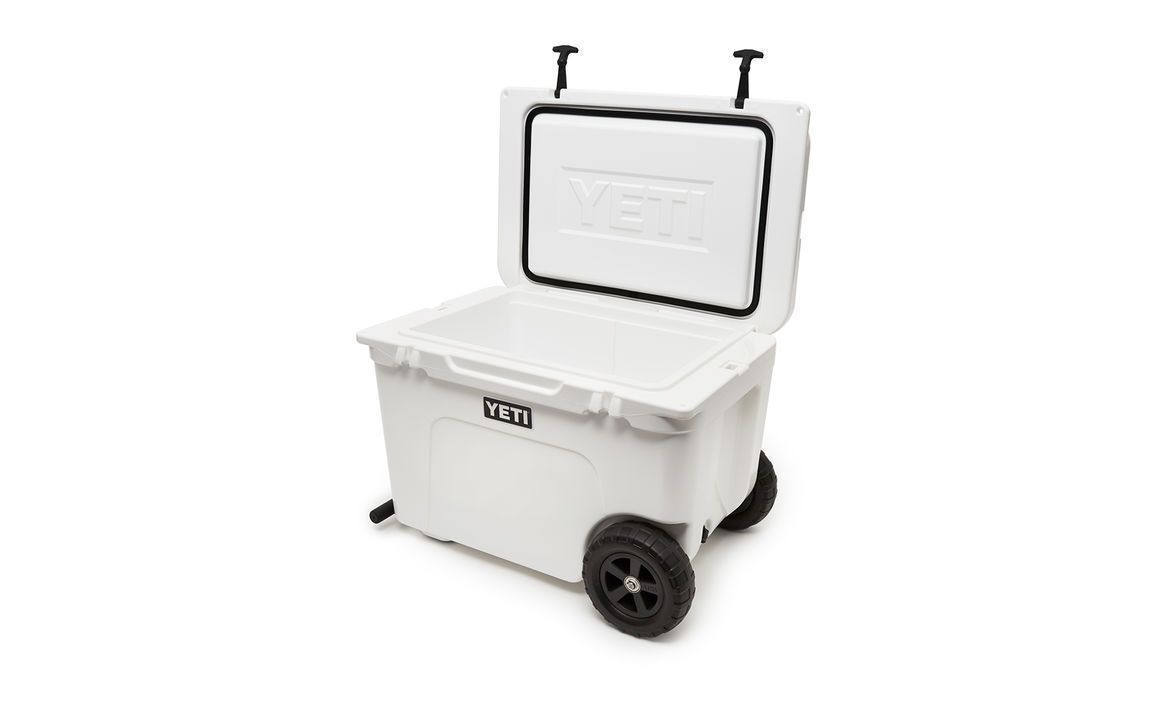 Eine weiße YETI® Kühlbox Tundra Haul mit geöffnetem Scharnierdeckel zeigt ihr leeres Inneres. Die tragbare Kühlbox verfügt über robuste schwarze Räder, Griffe und das YETI-Logo auf der Vorder- und Innenseite des Deckels.