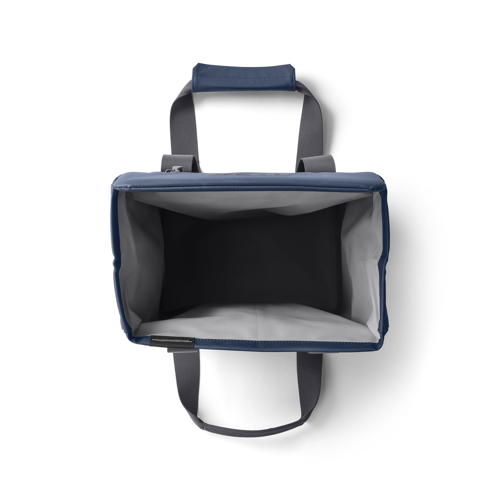 Draufsicht auf eine leere marineblaue und graue YETI® Kühltasche Daytrip Lunch Bag 14L mit breiter Öffnung, grauen Griffen, gepolstertem Griff und Coldcell Flex Isolierung für maximale Isolierung auf weißem Hintergrund.