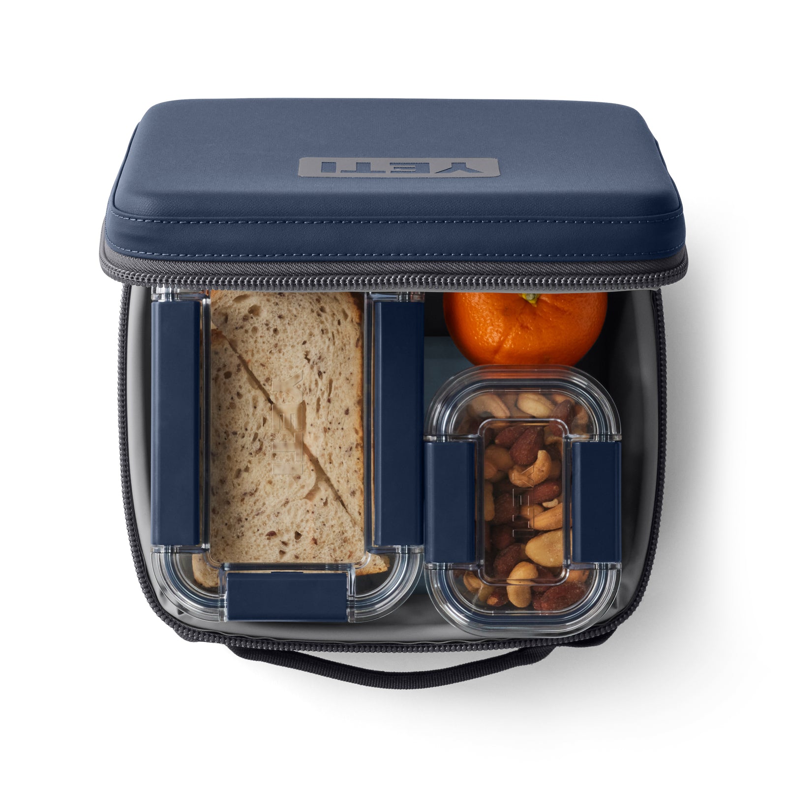Die YETI® Kühltasche Daytrip Lunch Box 3L in Navy von YETI bietet Platz für ein Sandwich, eine Orange und einen kleinen Behälter mit gemischten Nüssen mit durchsichtigen Deckeln, die alle ordentlich verpackt sind.