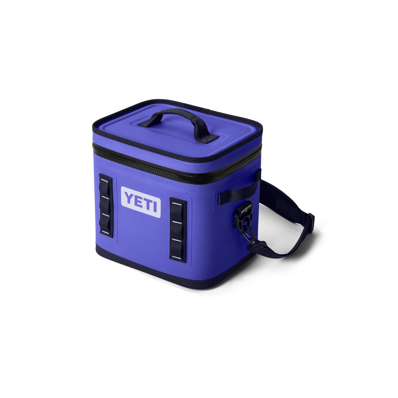 Die YETI® Kühltasche Hopper Flip® 12 in Ultramarine Violett verfügt über einen schwarzen Reißverschluss, schwarze Akzente, einen Griff an der Oberseite, zwei seitliche Gurte und einen verstellbaren Schultergurt auf weißem Hintergrund.