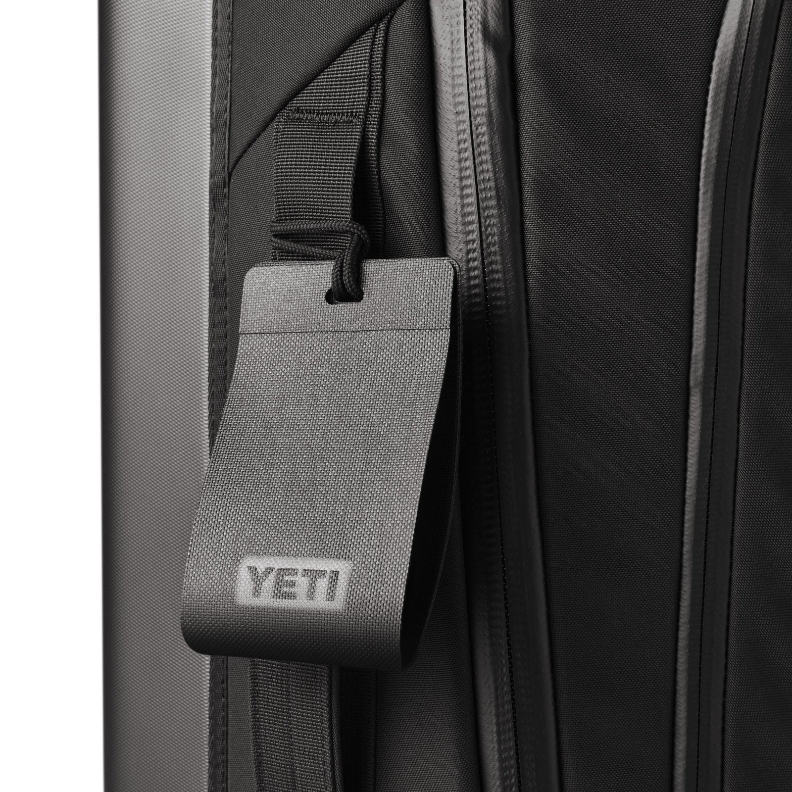 Nahaufnahme eines schwarzen YETI® Koffer Crossroads® 22 Gepäckanhängers mit geprägtem YETI-Logo, der am Griff dieses eleganten TuffSkin-Nylon-Handgepäcks von YETI befestigt ist.
