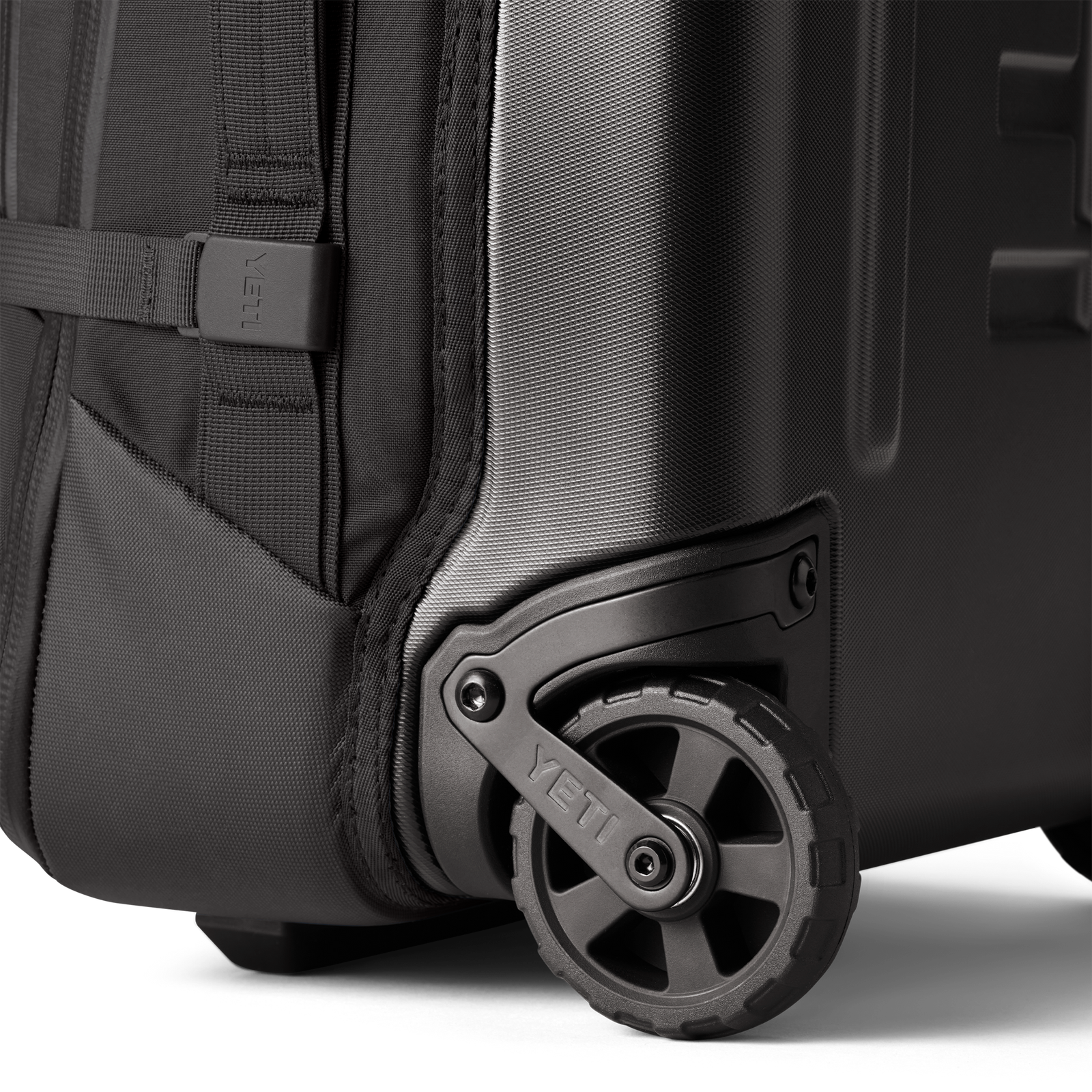 Nahaufnahme des YETI® Koffer Crossroads® 22 in Schwarz, die das robuste Rad, die strukturierte TuffSkin-Nylon-Hartschale, die verstärkten Kanten und die erstklassige YETI-Haltbarkeit zeigt.