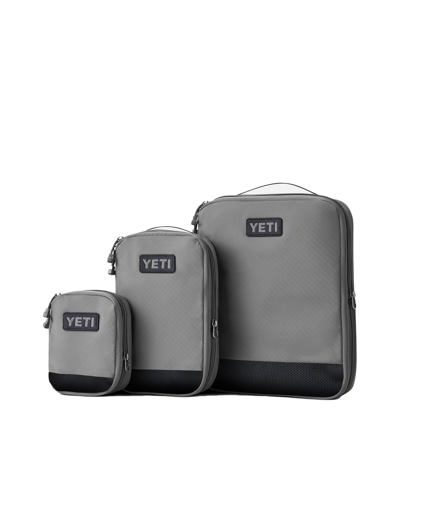 Drei graue YETI® Packtaschen - Crossroads Cubes L sind nebeneinander auf weißem Hintergrund abgebildet, jede mit einem Reißverschluss und dem YETI-Logo auf der Vorderseite.