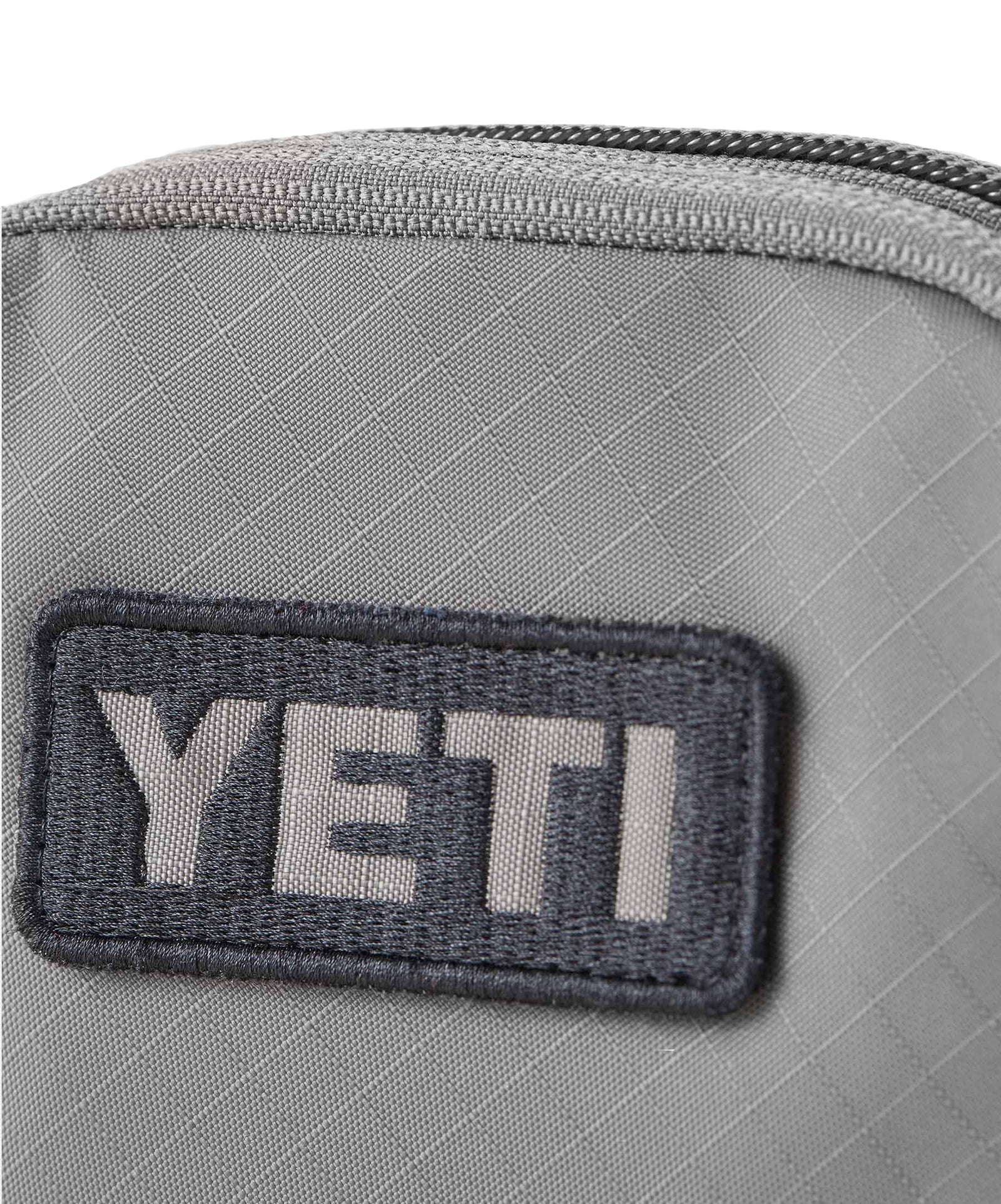 Nahaufnahme der grauen YETI® Packtaschen - Crossroads Cubes S, eines robusten Packwürfels mit einem dunklen gestickten YETI-Logoaufnäher und einem Reißverschluss an der Oberseite.
