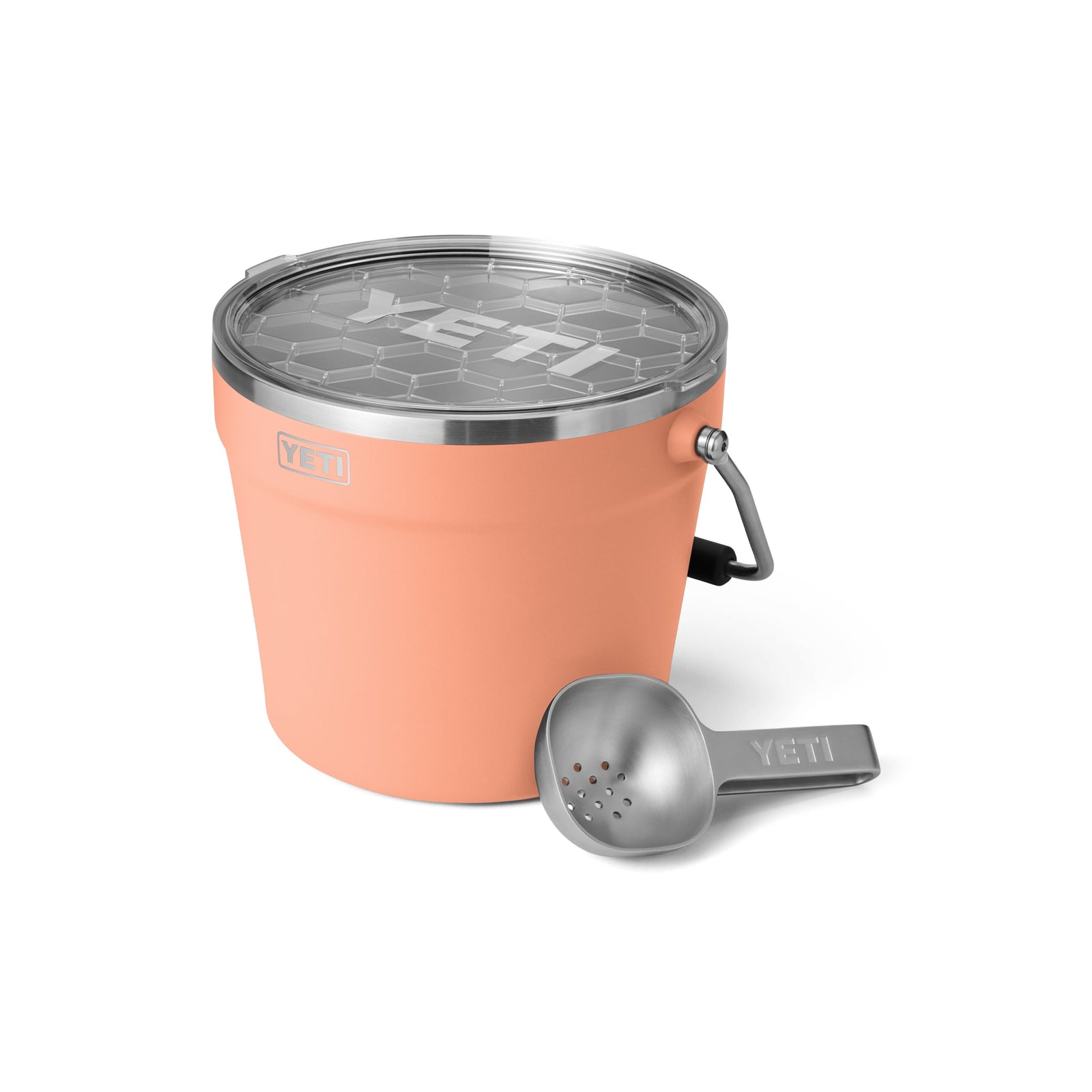 Ein YETI® Rambler® 7,6 Liter Getränkekübel in Lowcountry Peach mit doppelwandiger Vakuumisolierung und Metallgriff sitzt neben einem passenden Eisportionierer aus Metall auf einem weißen Hintergrund.