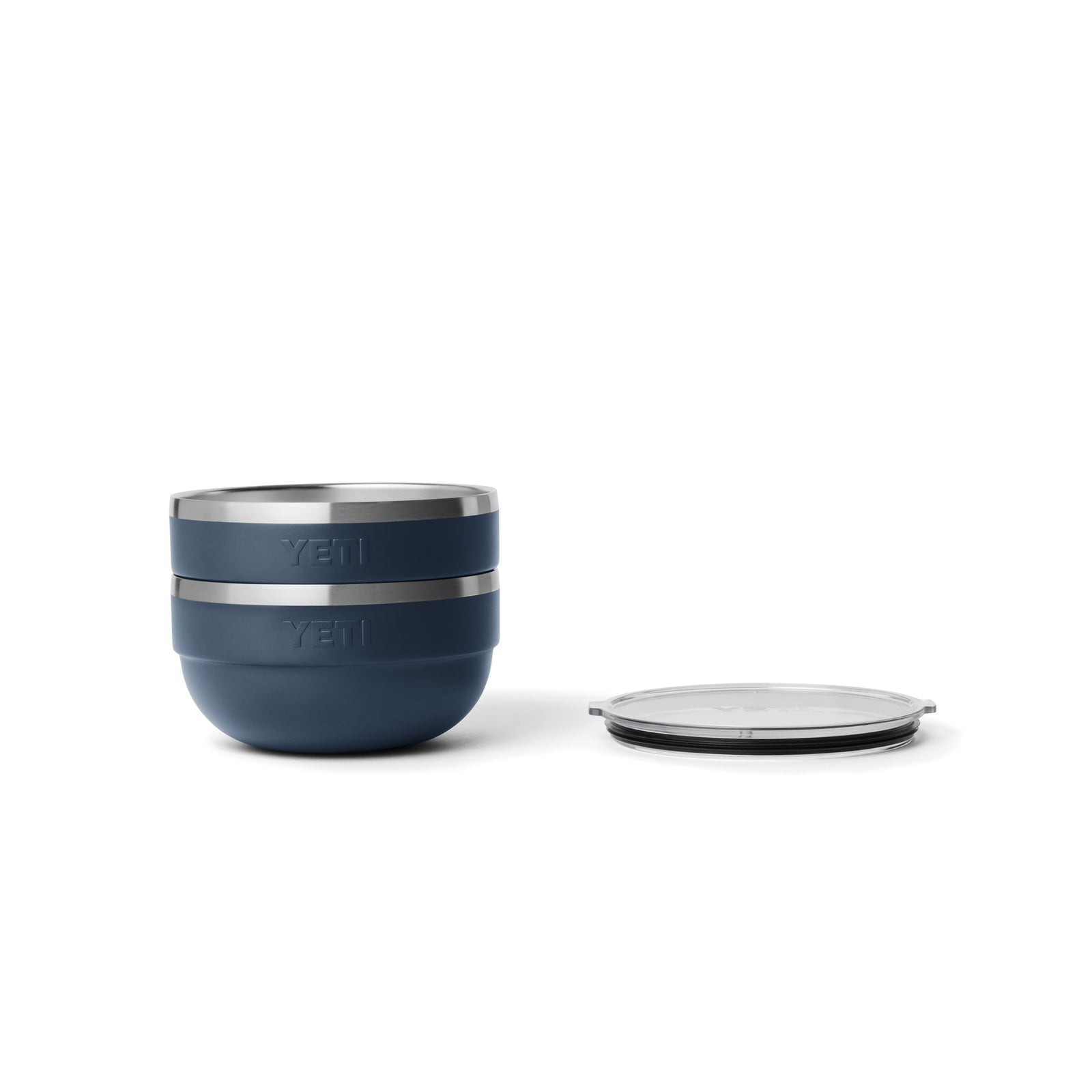 Links sind zwei gestapelte navyfarbene YETI® Rambler Bowl Mediums mit Edelstahlrand abgebildet, rechts ist ein klarer Kunststoffdeckel flach aufgesetzt, alles vor einem weißen Hintergrund.