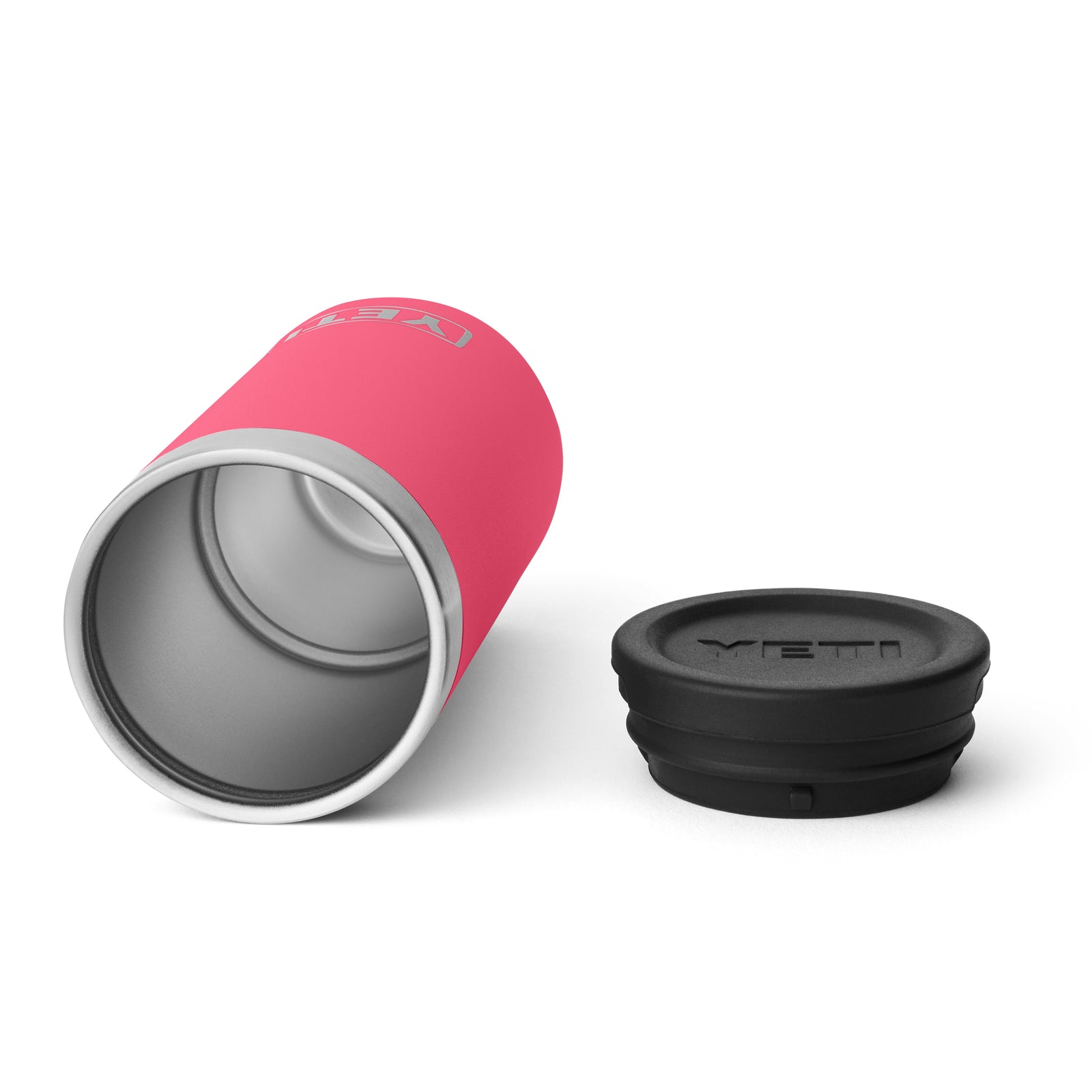 Ein YETI® Rambler Schnapsbecher in Tropical Pink liegt seitlich neben einem schwarzen Deckel mit YETI Logo auf weißem Hintergrund.