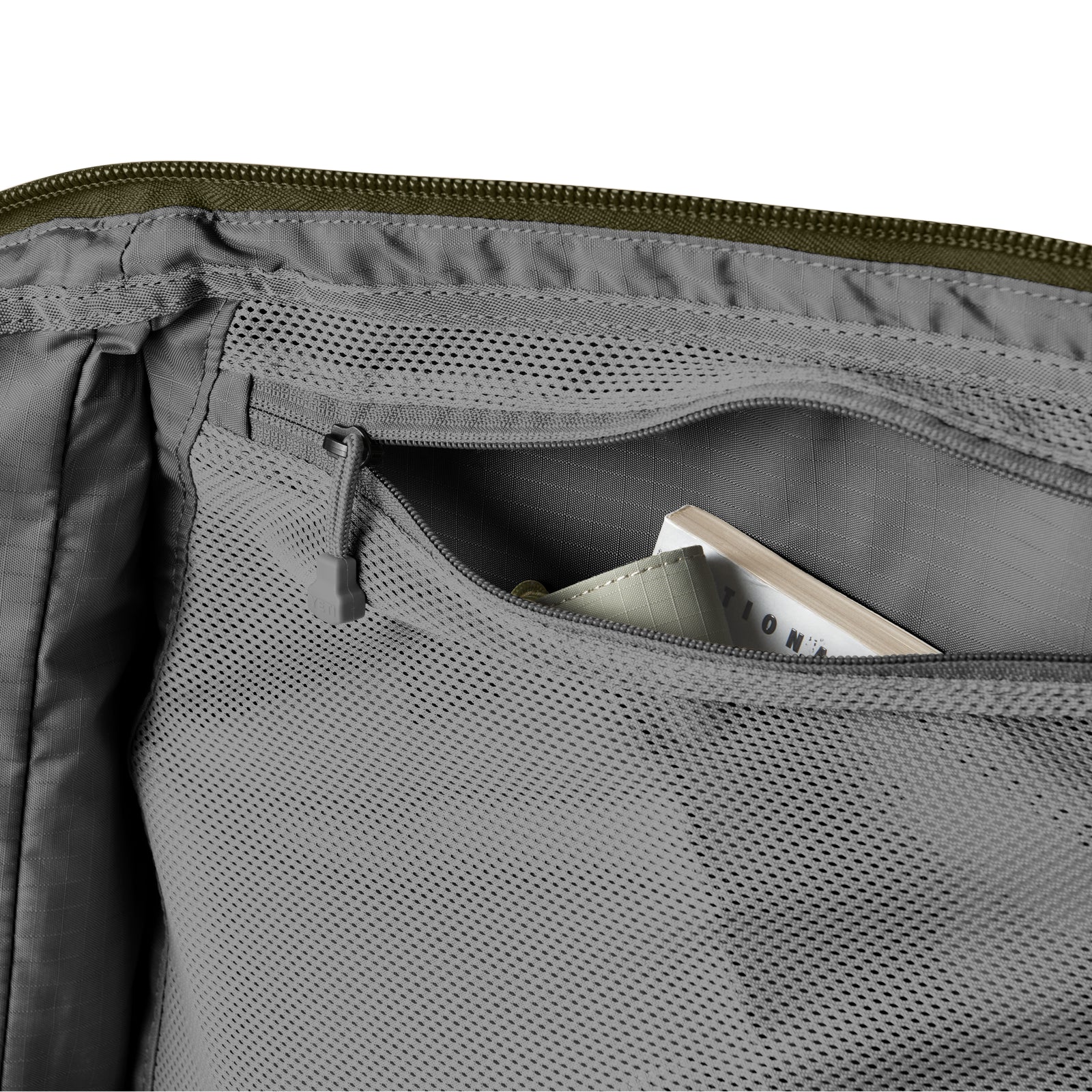 Nahaufnahme der grauen Netztasche mit Reißverschluss im Inneren der YETI® Reisetasche Crossroads® 60L - Olive. Die aus robustem TuffSkin-Nylon gefertigte, teilweise geöffnete Tasche bietet Platz für ein kleines Notizbuch und einen anderen sicheren Gegenstand.