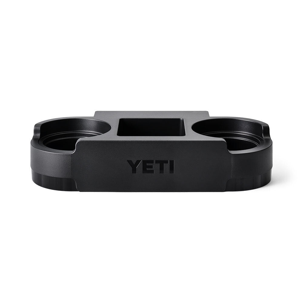 Der YETI® Roadie 48/60 Dual Cupholder ist ein schwarzes Zubehörteil mit zwei runden Schlitzen und einem zentralen rechteckigen Fach, perfekt für Getränke und kleine Gegenstände. Kompatibel mit YETI Roadie 48/60 Kühlboxen.