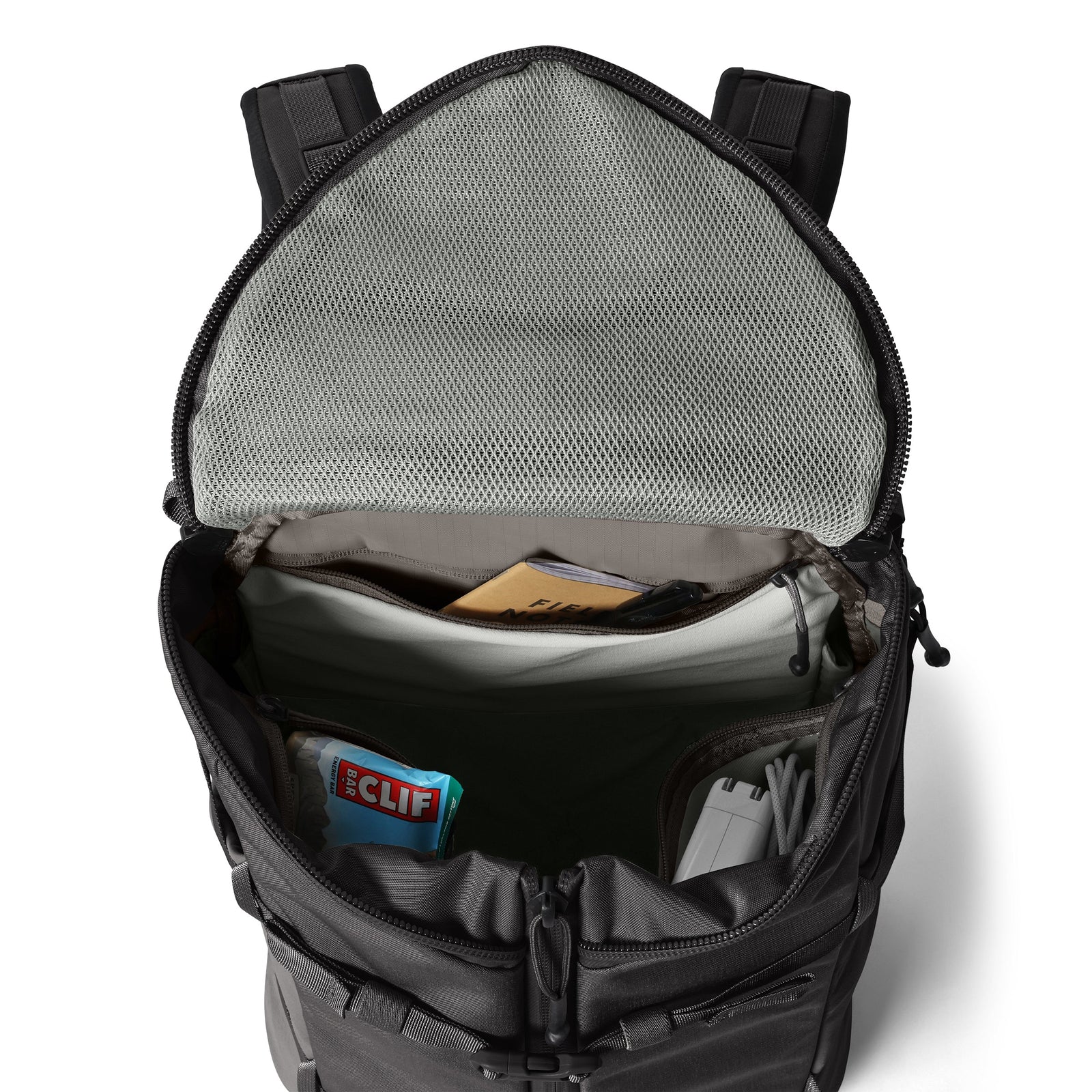 Ein geöffneter schwarzer YETI® Rucksack Ranchero™ 27L gibt den Blick auf organisierte Fächer, ein Laptopfach und eine Netztasche im Deckel frei, in der ein Clif Bar, Kabel, Dokumente und andere kleine Gegenstände ordentlich verstaut werden können.