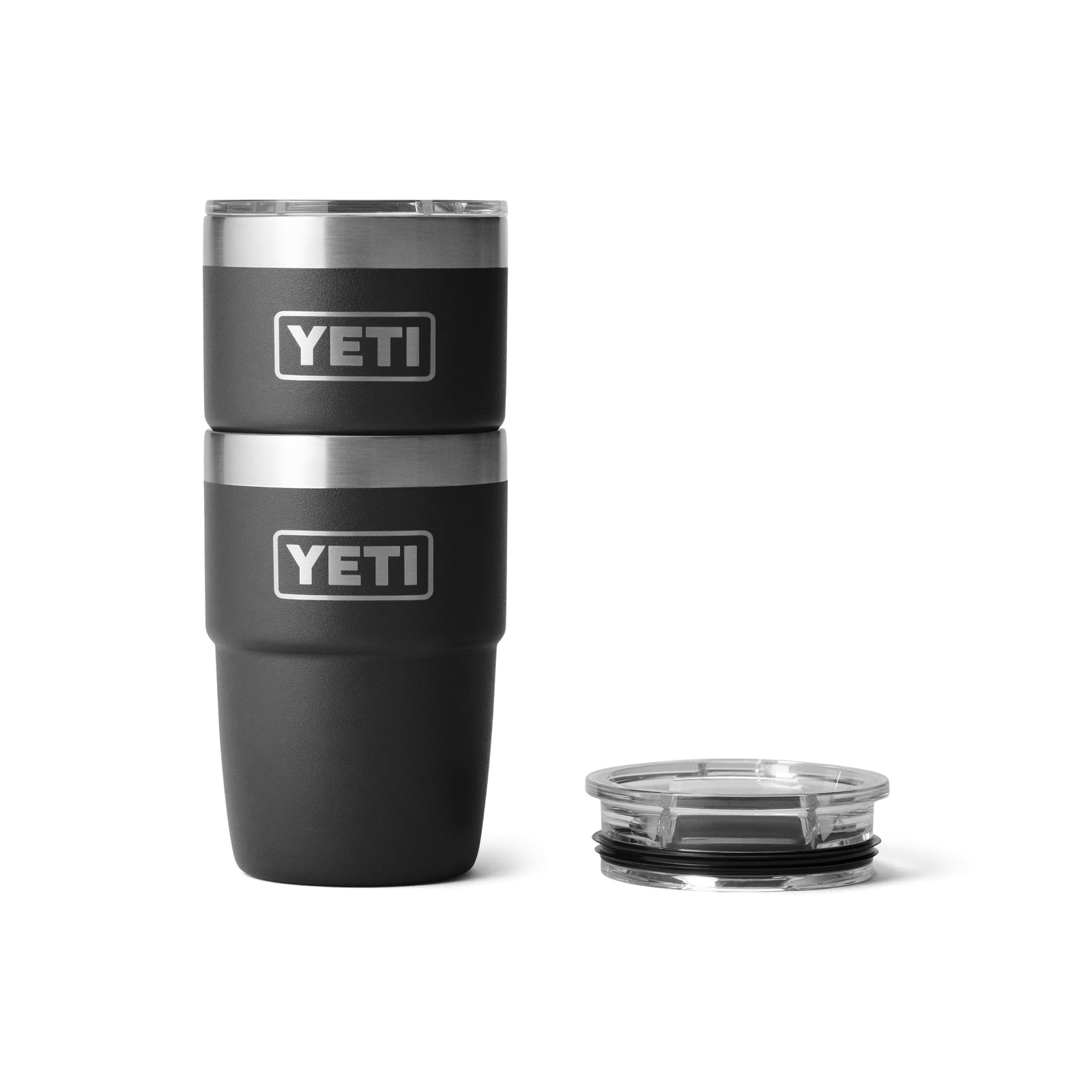 Zwei schwarze YETI® Stapelbarer Becher Rambler 8 Oz Becher mit silbernen Rändern und Logos sind auf der linken Seite gestapelt, während ein klarer Plastikdeckel auf der rechten Seite platziert ist, alles vor einem weißen Hintergrund.