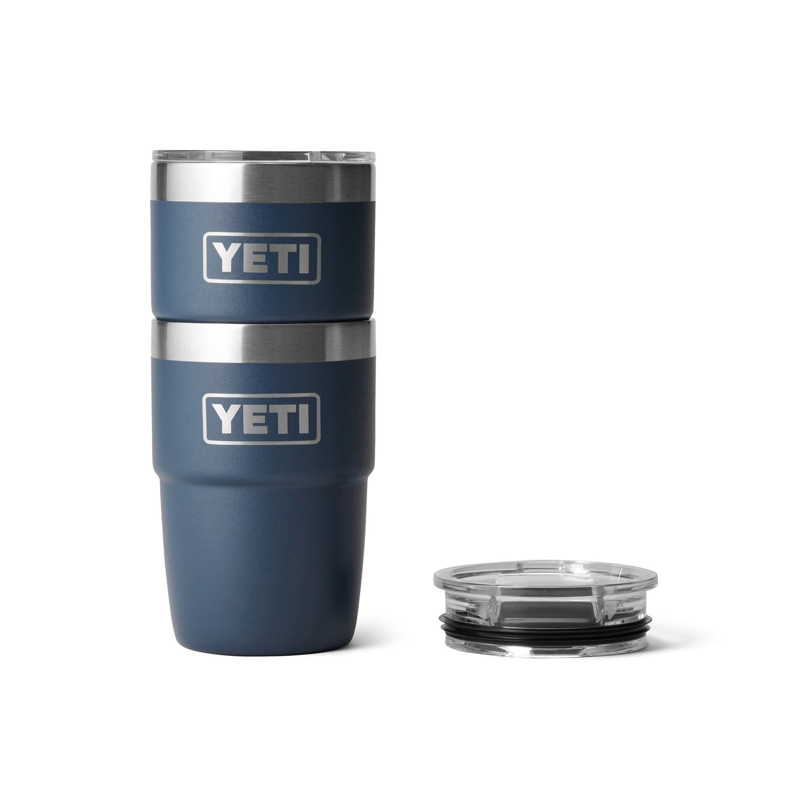 Zwei YETI® Stapelbarer Becher Rambler 8 Oz - Navy Becher mit doppelwandiger Vakuumisolierung sind neben einem durchsichtigen Kunststoffdeckel gestapelt, alles vor einem schlichten weißen Hintergrund.