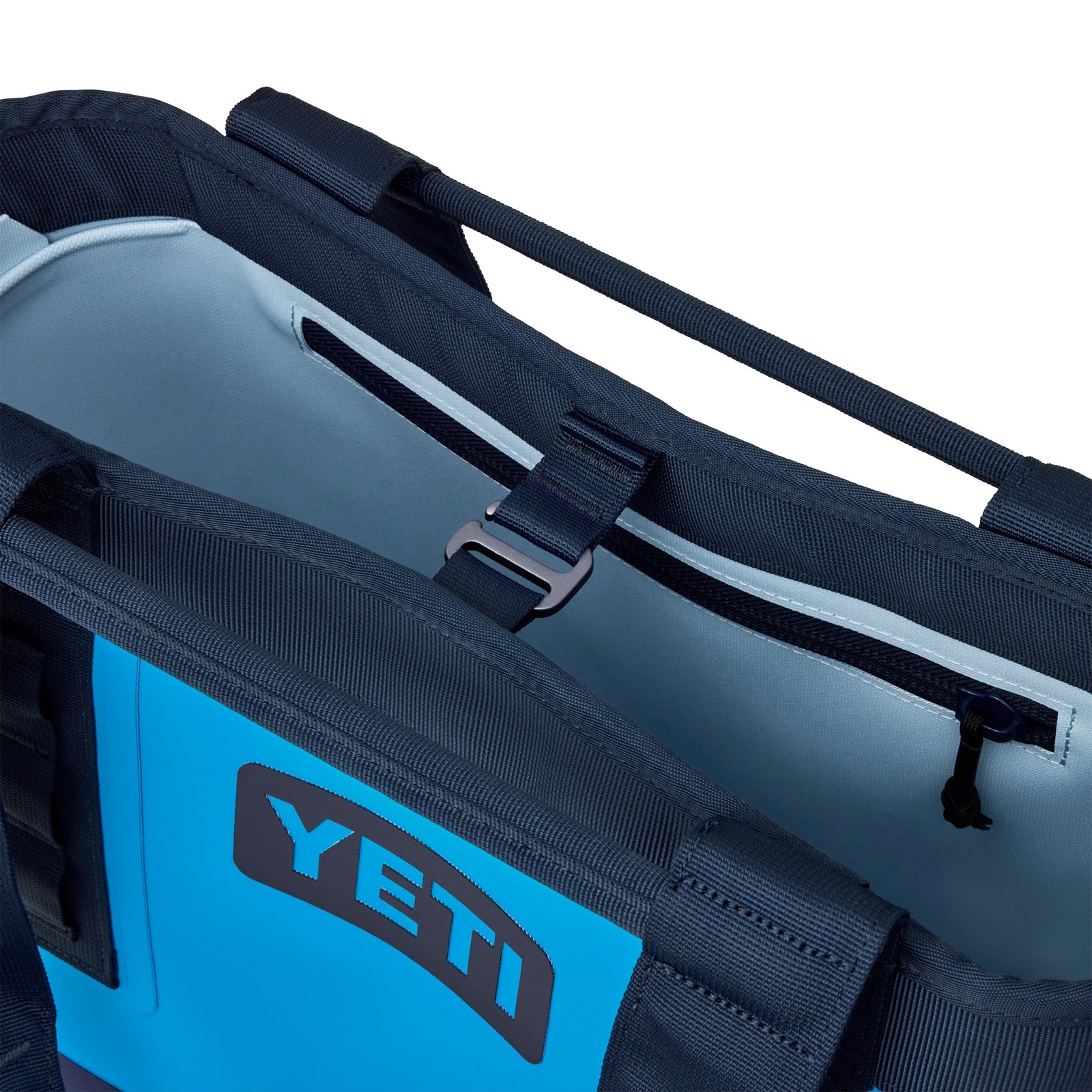 Nahaufnahme des Innenraums der YETI® Tragetasche Camino® Carryall 20 - Big Wave Blue. Hervorzuheben sind die Reißverschlusstasche, der Schnallenriemen, die stabilen Griffe und das YETI-Logo - eine stilvolle, wasserdichte Tasche für jedes Abenteuer.