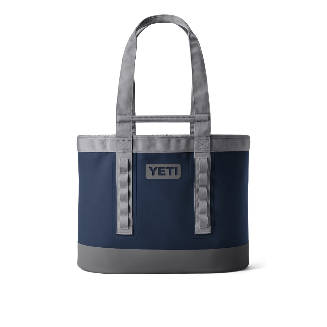 Die YETI® Tragetasche Camino® Carryall 50 - Navy hat ein rechteckiges, wasserdichtes Design mit zwei stabilen grauen Griffen, einem YETI-Logoaufnäher auf der Vorderseite und einem minimalistischen, strukturierten Look, der sowohl stilvoll als auch langlebig ist.