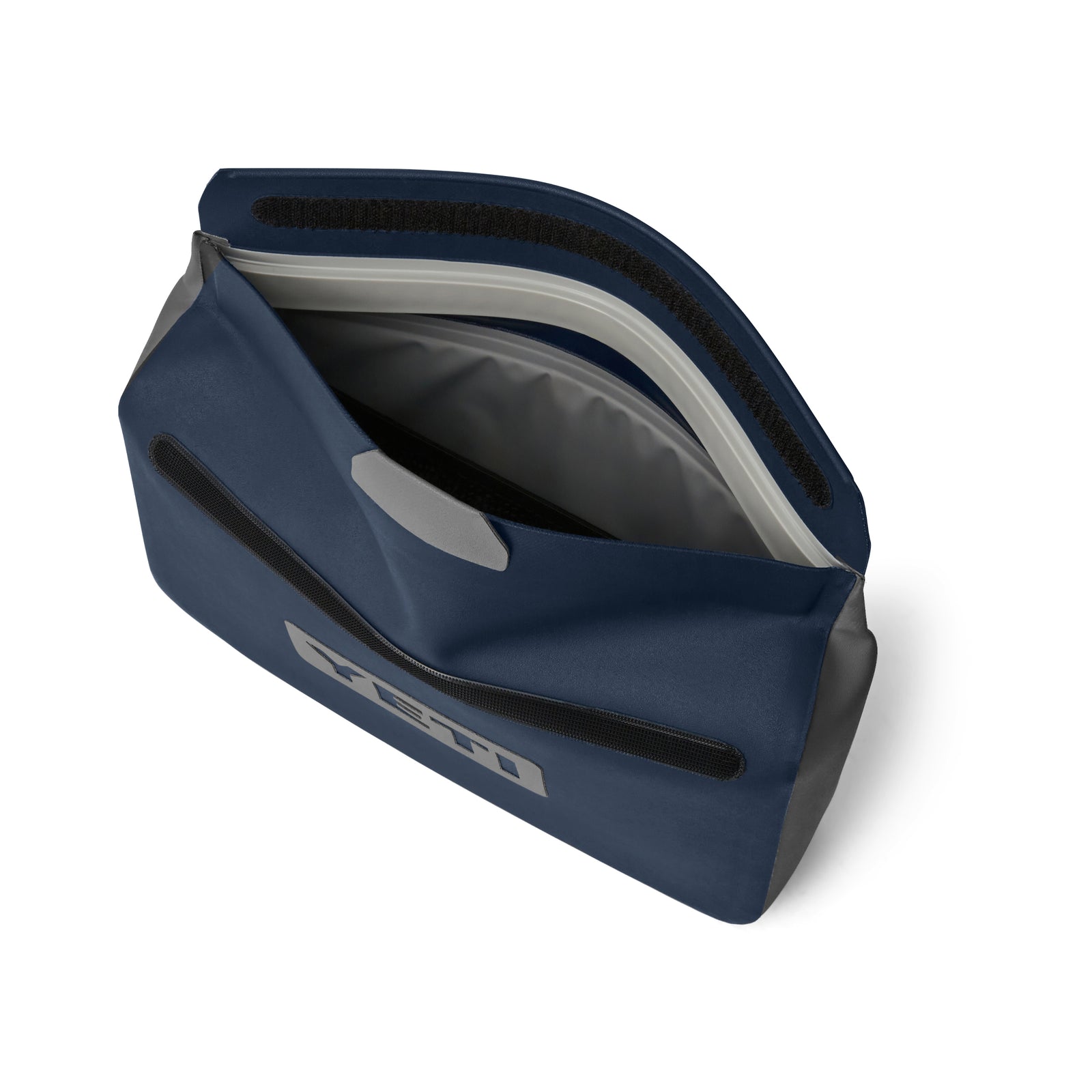 Die YETI® Zubehörtasche - Sidekick® 3L in Navy ist geöffnet und zeigt ihr geräumiges, wasserdichtes Inneres. Sie verfügt über einen schwarzen Reißverschluss mit Klettverschlusslasche, einen Tragegriff und das YETI-Logo auf der Vorderseite.
