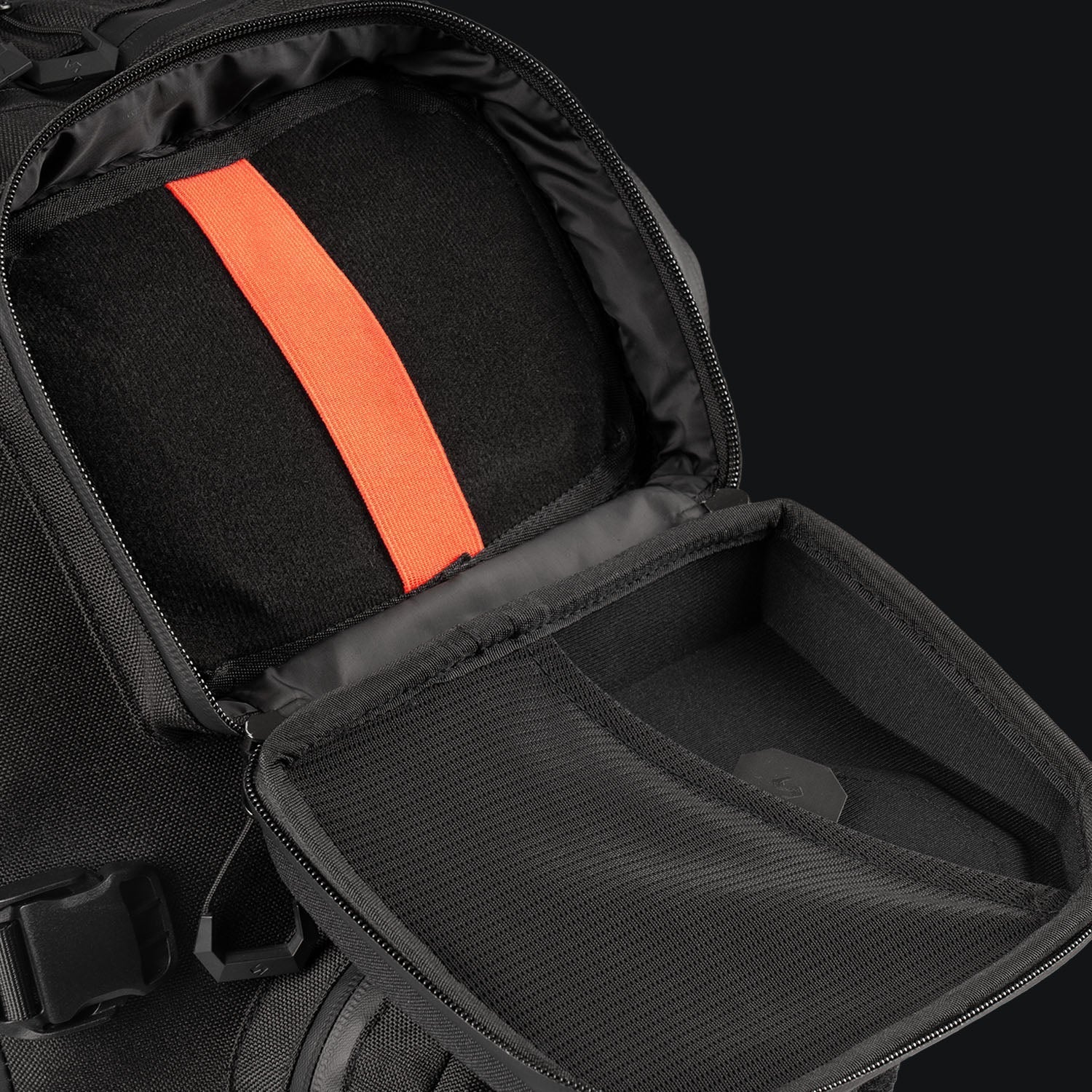 Eine Nahaufnahme des geöffneten STOIRM 40L Tactical Pack GEN2 von STOIRM vor einem dunklen Hintergrund, der das Innere mit einem leuchtend orangefarbenen Gurt und einer Netztasche im Inneren der Klappe hervorhebt.