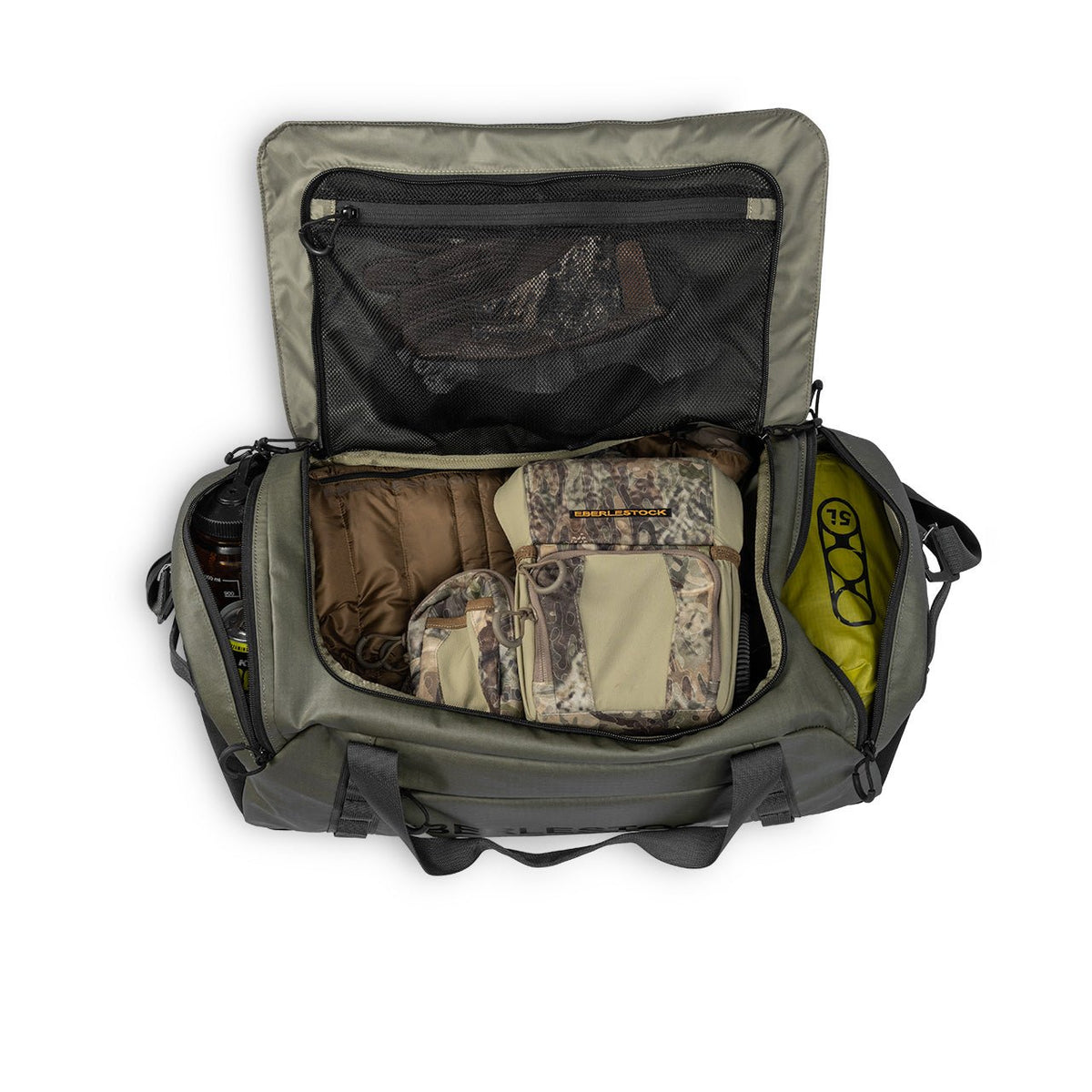 Eine offene EBERLESTOCK Hyllus Duffel 65 in Military Green, 65L, von oben betrachtet, zeigt organisierte Fächer für Tarnkleidung, braune Kleidung, einen gelben Packsack und andere Ausrüstung.