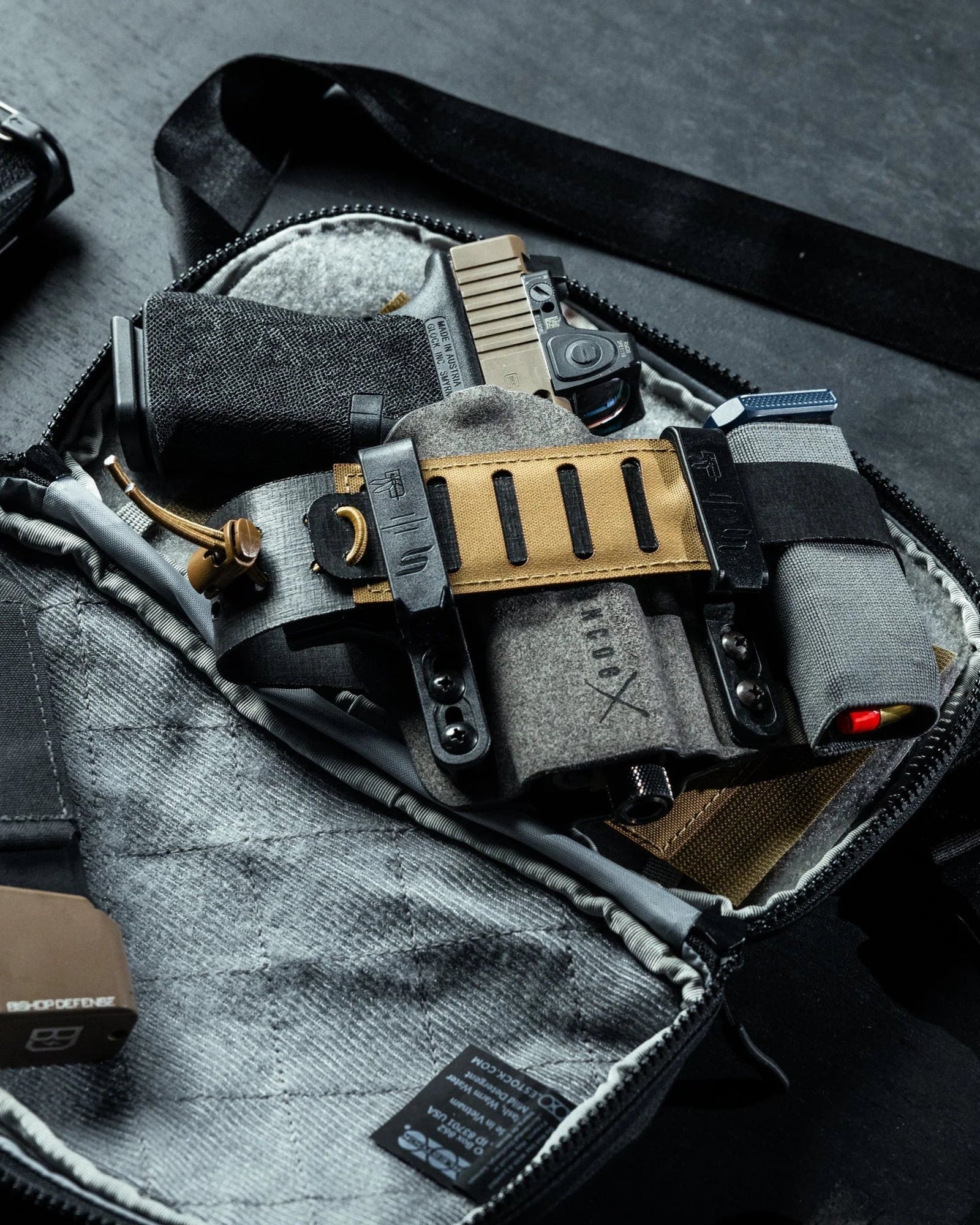 Die EBERLESTOCK Fade Flex Crossbody-Bag lässt sich öffnen und gibt den Blick frei auf eine verdeckte Tragevorrichtung mit Pistole, Rotpunktvisier, Mag-Trägern und Zubehör auf einer braunen MOLLE-Platte - ideal für Eberlestock Fade Flex Fans.