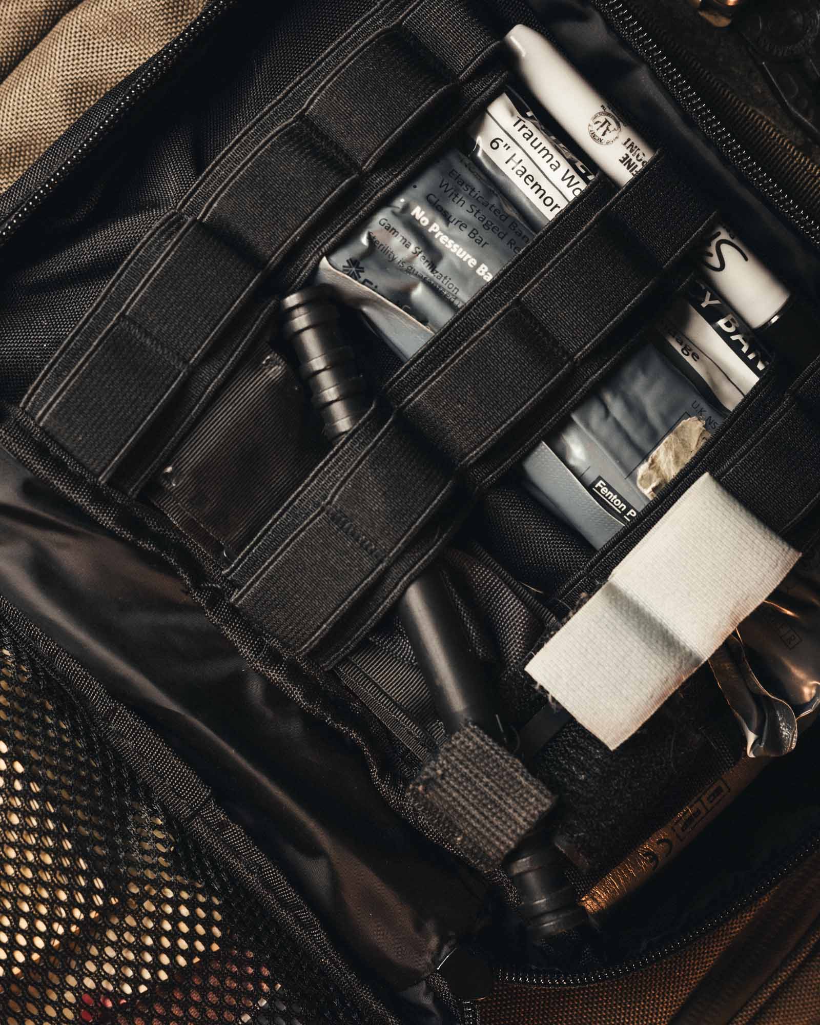 Eine Nahaufnahme der STOIRM Large Pouch V.1 von STOIRM zeigt in elastischen Schlaufen an der Molle-Panel-Tasche organisierte Wundauflagen, ein Tourniquet und andere Erste-Hilfe-Utensilien.