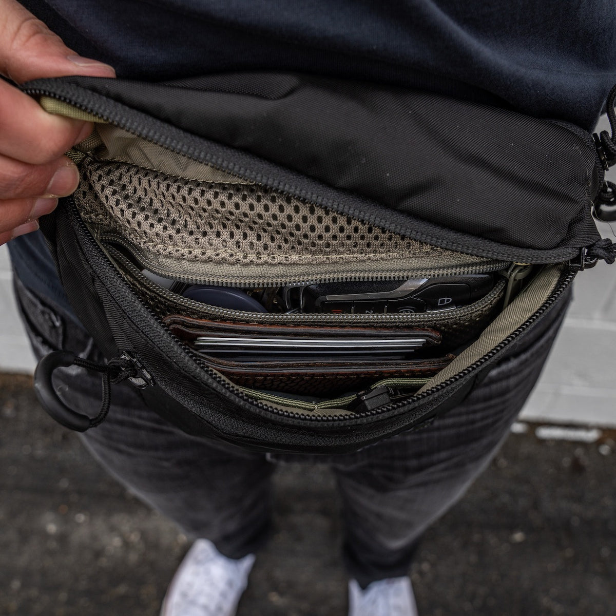 Eine Hand öffnet die EBERLESTOCK Bando Bag Standard und gibt den Blick frei auf organisierte Innenfächer für Brieftasche, Schlüssel, Karten, ein Netzfach und ein spezielles CCW-Fach.
