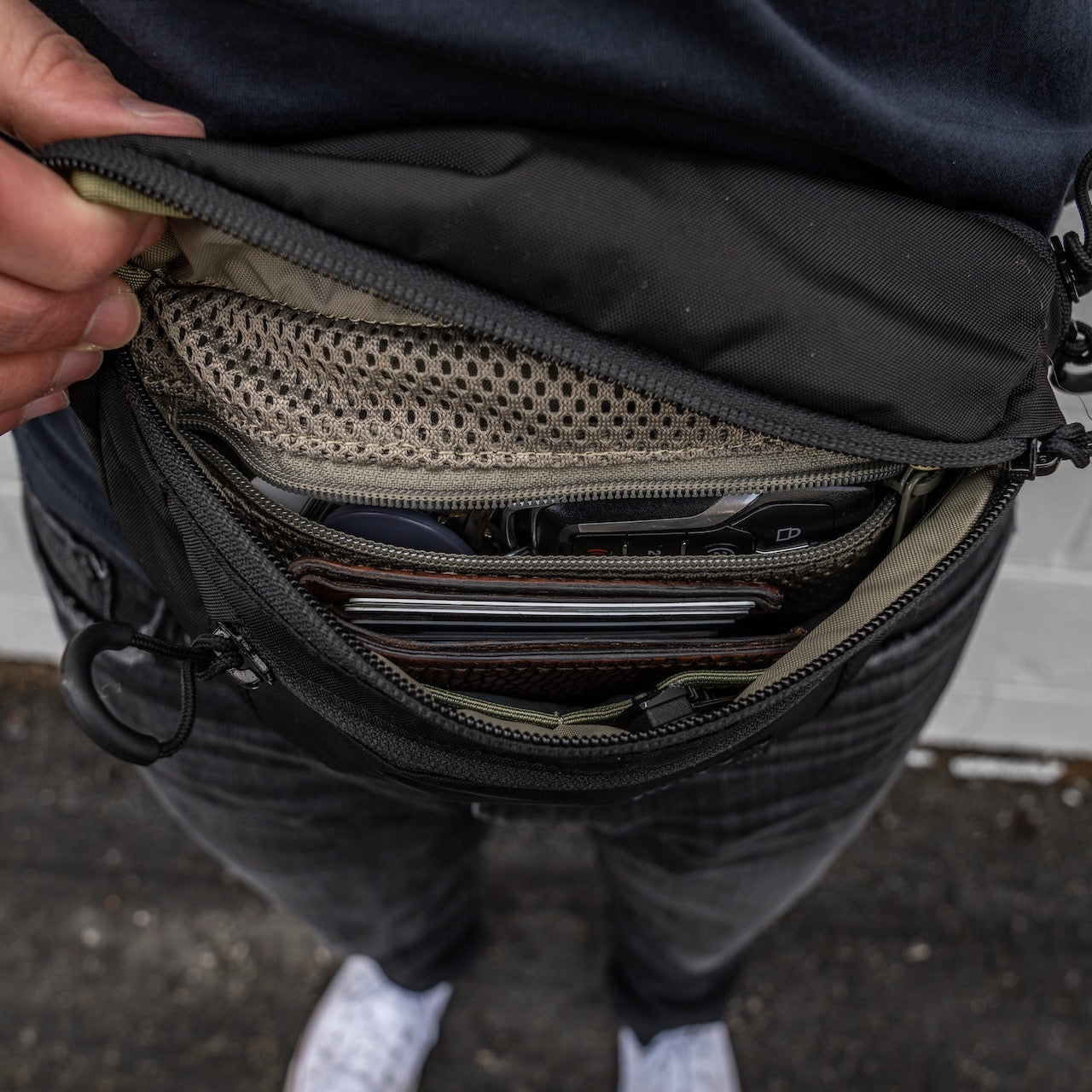 Eine Hand öffnet die EBERLESTOCK Bando Bag Standard und gibt den Blick frei auf organisierte Innenfächer für Brieftasche, Schlüssel, Karten, ein Netzfach und ein spezielles CCW-Fach.