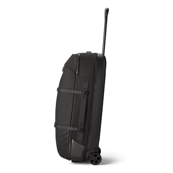 Der YETI® Koffer Crossroads® 29'' - Black, ein robuster Hartschale-Reisekoffer mit zwei Rollen und ausziehbarem Teleskopgriff, steht aufrecht im Profil vor weißem Hintergrund.