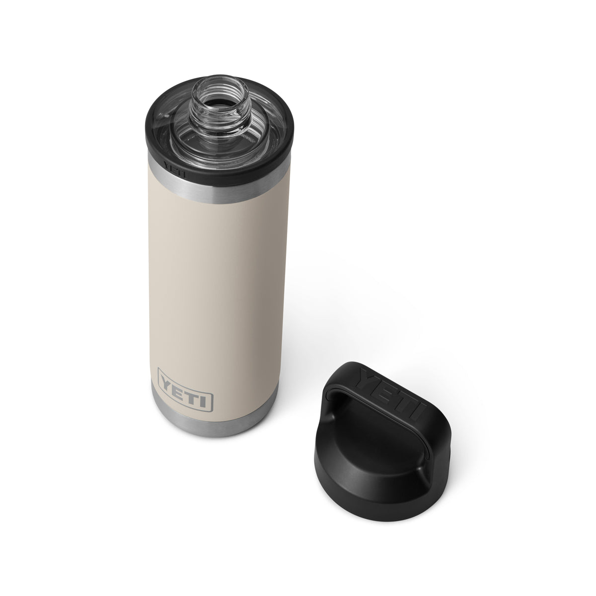 Die YETI® Flasche Rambler 18 Oz in Cape Taupe mit doppelwandiger Vakuumisolierung und Edelstahlrand steht auf weißem Hintergrund, daneben liegt der schwarze abgenommene Deckel, die offene Öffnung zeigt nach oben.