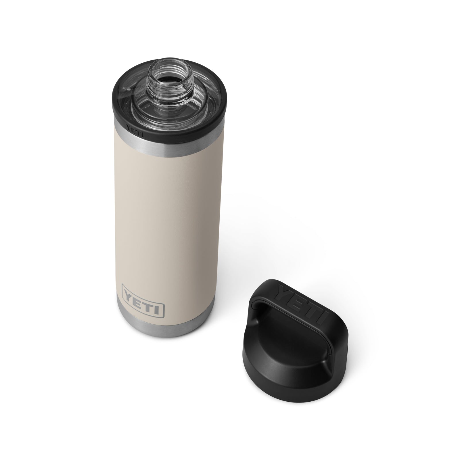 Die YETI® Flasche Rambler 18 Oz in Cape Taupe mit doppelwandiger Vakuumisolierung und Edelstahlrand steht auf weißem Hintergrund, daneben liegt der schwarze abgenommene Deckel, die offene Öffnung zeigt nach oben.
