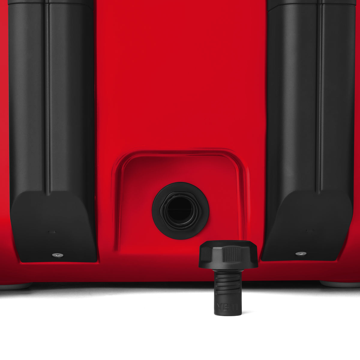 Nahaufnahme der YETI® Kühlbox Roadie 32 - Rescue Red mit zwei schwarzen Fächern, einer zentralen Abflussöffnung und einem schwarzen YETI-Gewindedeckel, der sich darunter befindet und befestigt werden kann.