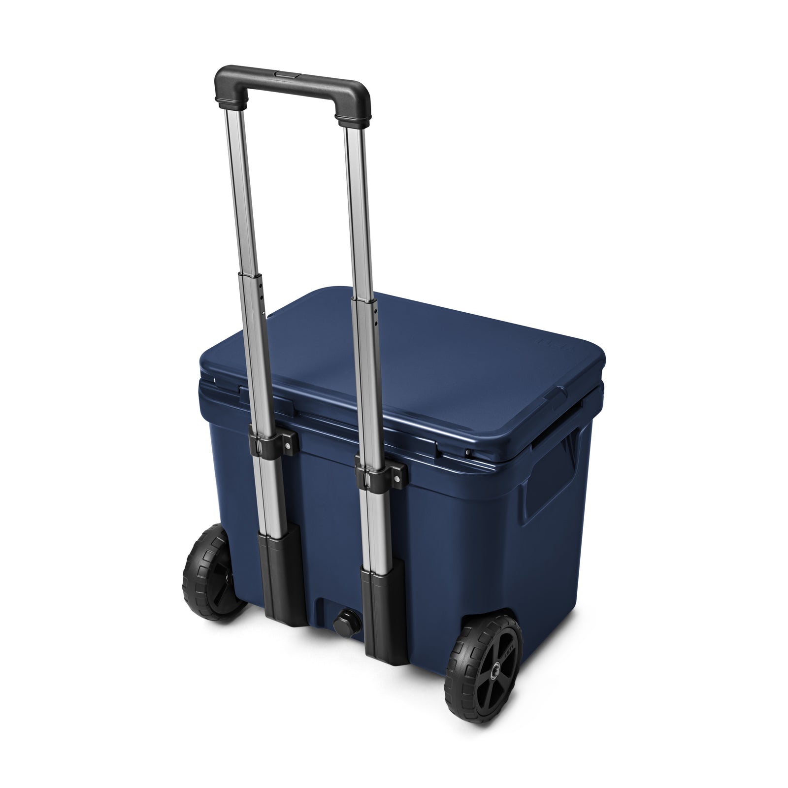 Eine YETI® Kühlbox Roadie 60 - Navy ist mit geschlossenem Deckel und aufrechtem Griff auf weißem Hintergrund abgebildet. Die Kühlbox verfügt über zwei große schwarze Räder und geformte Seitengriffe für den bequemen Transport.