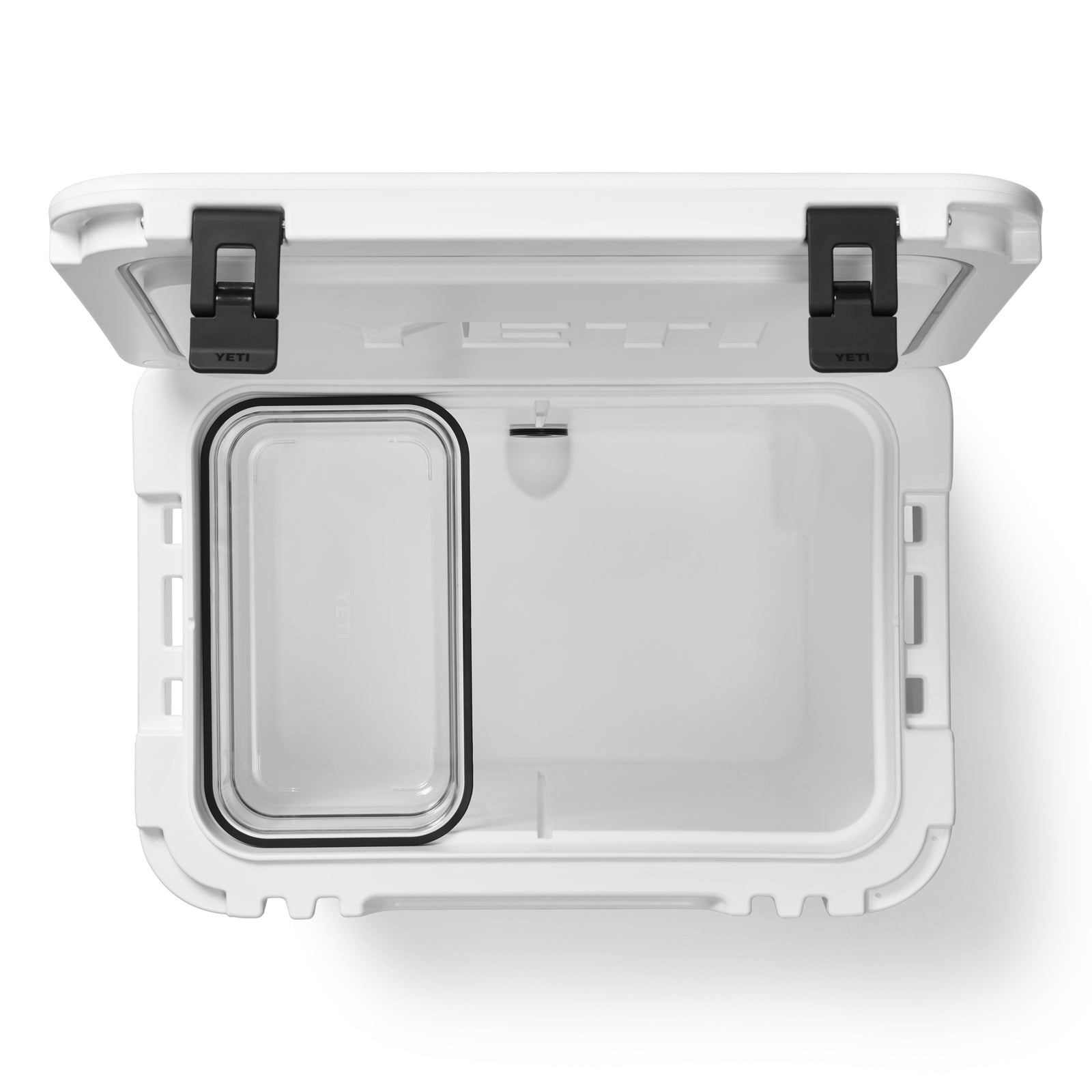 Draufsicht auf eine geöffnete weiße YETI® Kühlbox Roadie 60 mit schwarzen Verschlüssen, mit einem leeren Hauptfach und einem durchsichtigen Kunststoffbehälter, der die leistungsstarke Isolierung der Marke zeigt.