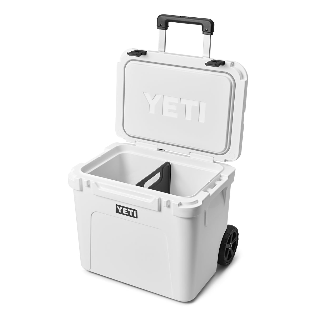 Die YETI® Kühlbox Roadie 60 - White ist mit geöffnetem Deckel abgebildet, der einen unterteilten Innenraum für eine einfache Organisation zeigt. Der YETI Markenname erscheint sowohl auf dem Deckel als auch auf der Vorderseite dieser Camping-Kühlbox.