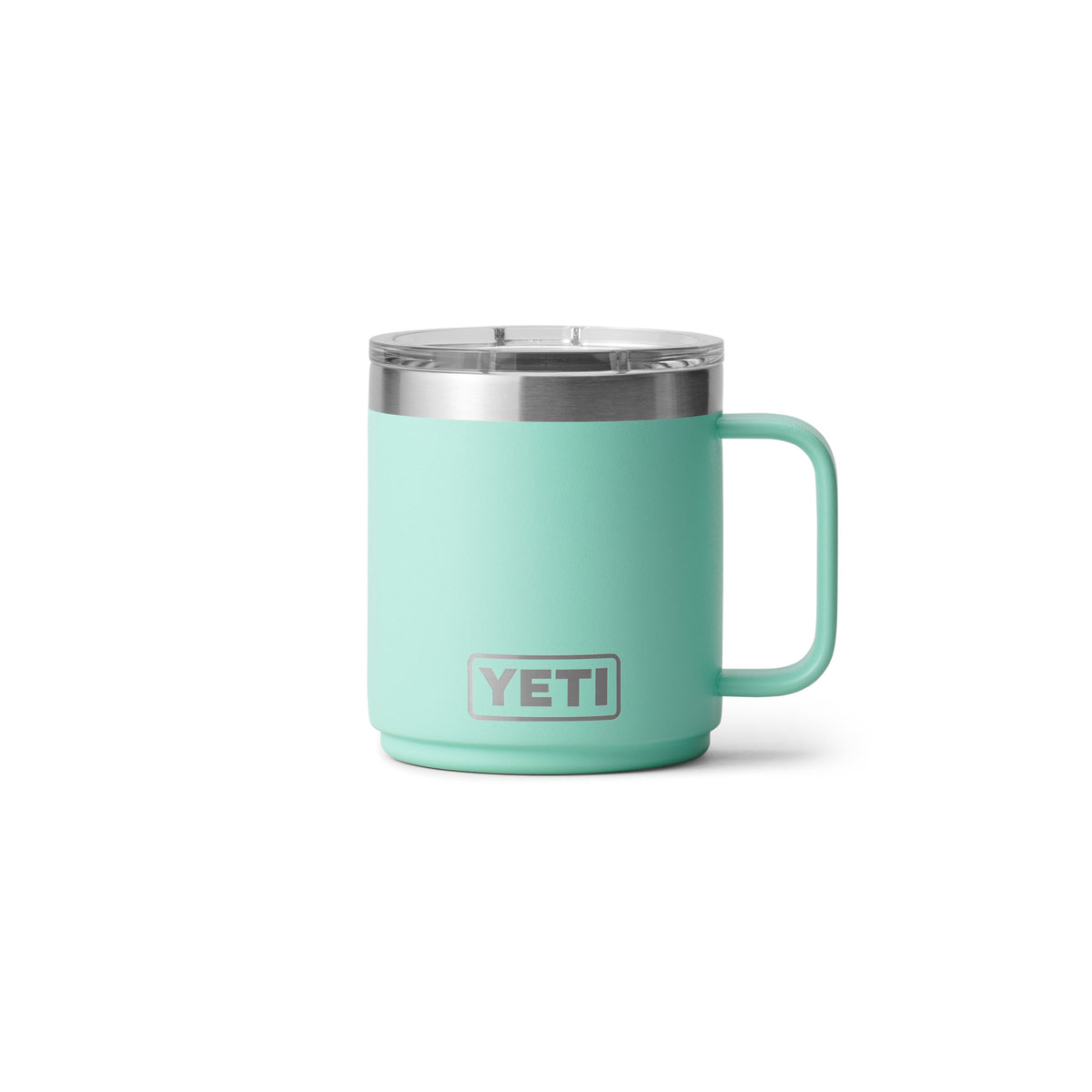 Eine YETI® Tasse Rambler 10 Oz in Seafoam mit Edelstahl-Deckel und Henkel sowie doppelwandiger Vakuumisolierung steht vor weißem Hintergrund, das YETI Logo ist auf der Vorderseite der Keramiktasse sichtbar.