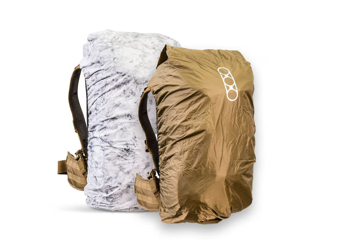 Zwei große EBERLESTOCK Rucksäcke mit der Eberlestock Rucksack-Regenhülle Large wendbar - Coyote / D. Winter sind nebeneinander abgebildet; der eine trägt eine weiß marmorierte Regenhülle, der andere eine braune mit weißem Logo, beide mit schwarzen Schultergurten.