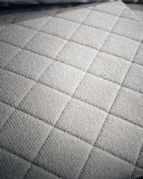 Die Nahaufnahme des Eberlestock Fade Sling XL von EBERLESTOCK zeigt einen hellgrauen, gesteppten Stoff mit quadratischem Muster, der seine weiche, gepolsterte Textur hervorhebt - ideal für das tägliche Tragen oder die Verwendung als vielseitige Tragetasche.