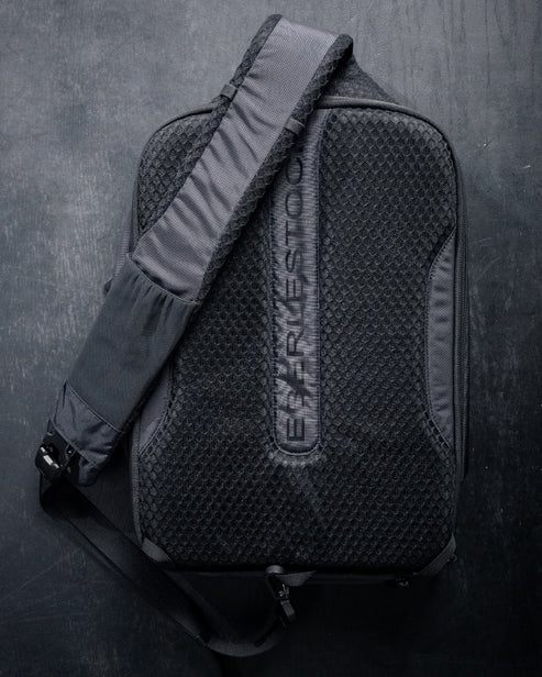 Ein schwarzer, strukturierter Eberlestock Fade Sling XL mit einem breiten, verstellbaren Schultergurt sitzt auf einer dunklen Oberfläche. Die Marke EBERLESTOCK ist vertikal auf der Vorderseite eingeprägt, was sie zu einer stilvollen Wahl für Ihre EDC-Essentials macht.