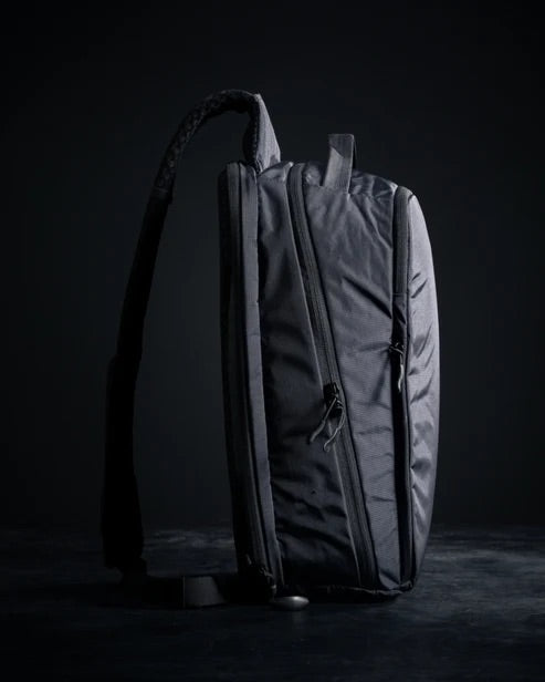 Der EBERLESTOCK Fade Sling XL Rucksack, aufrecht auf dunklem Hintergrund, verfügt über einen einzigen Tragegurt und mehrere Reißverschlusstaschen - ideal für den Transport Ihrer täglichen Ausrüstung.