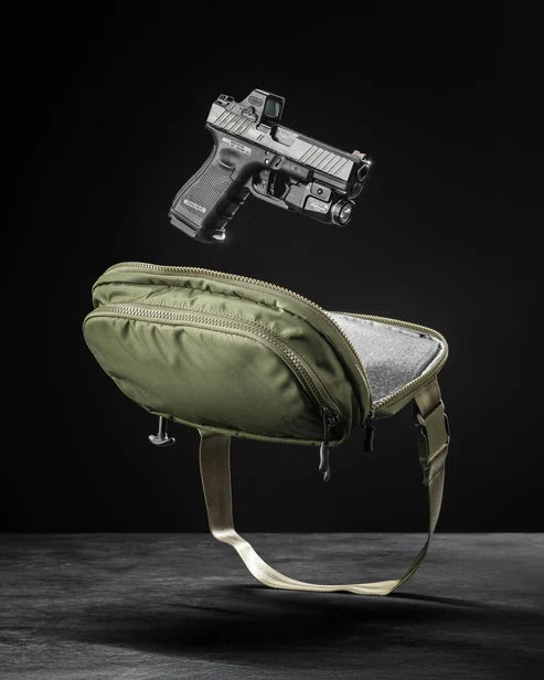 Eine schwarze Handfeuerwaffe schwebt über einer offenen EBERLESTOCK Fade Flex Micro Tasche mit beigen Riemen vor einem dunklen Hintergrund.