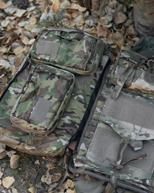 Tarnfarbene taktische Ausrüstungsgegenstände und Taschen, darunter die EBERLESTOCK Rip-Away Medical Pouch Large, sind auf herabgefallenen Blättern verstreut - die ideale medizinische Ausrüstung für den militärischen oder Outdoor-Einsatz.