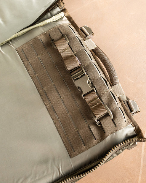 Nahaufnahme des EBERLESTOCK Spectre Rucksacks mit MOLLE-Gewebe, stabilem Griff und verstellbarem Schnallenriemen auf hellbrauner Oberfläche.
